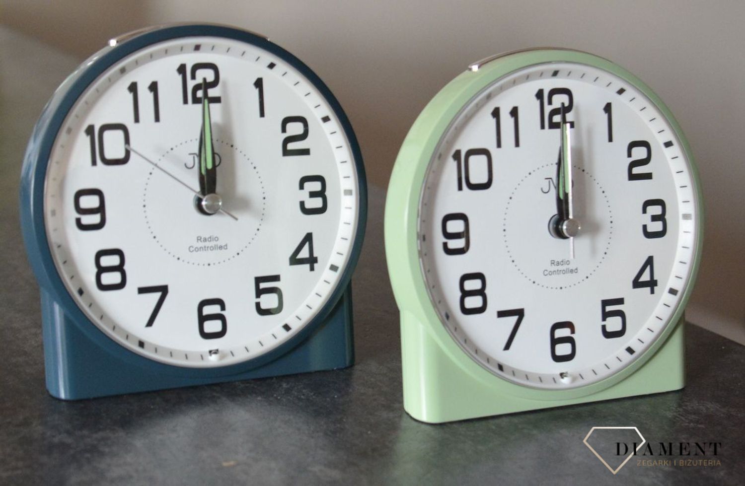 Budzik klasyczny JVD sterowany radiowo zielony RB22.2.  Jest realizowane za pomocą panelu którego aktywacja powoduje świecenie całego wyświetlacza za pomocą przycisku. Podświetlenie jest w kolorze pomarańczo.jpg