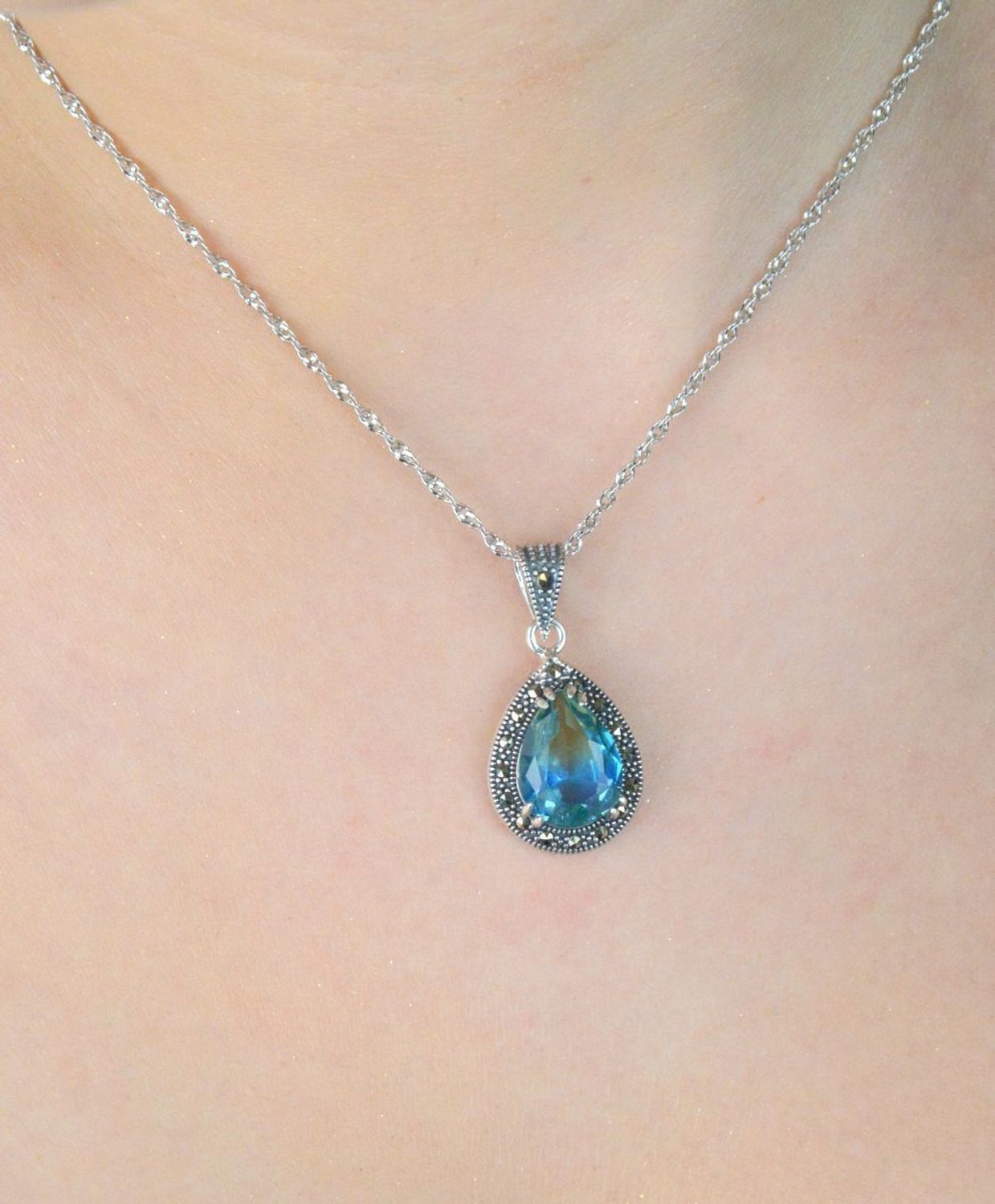 Zawieszka srebrna próby 925 w kształcie łezki, zdobiona cyrkonią niebiesko-zieloną i markazytami. Model DIA-ZAW-13186-925, długość 3,0 cm, szerokość 1,5 cm, waga 3,20 g. 1.jpg