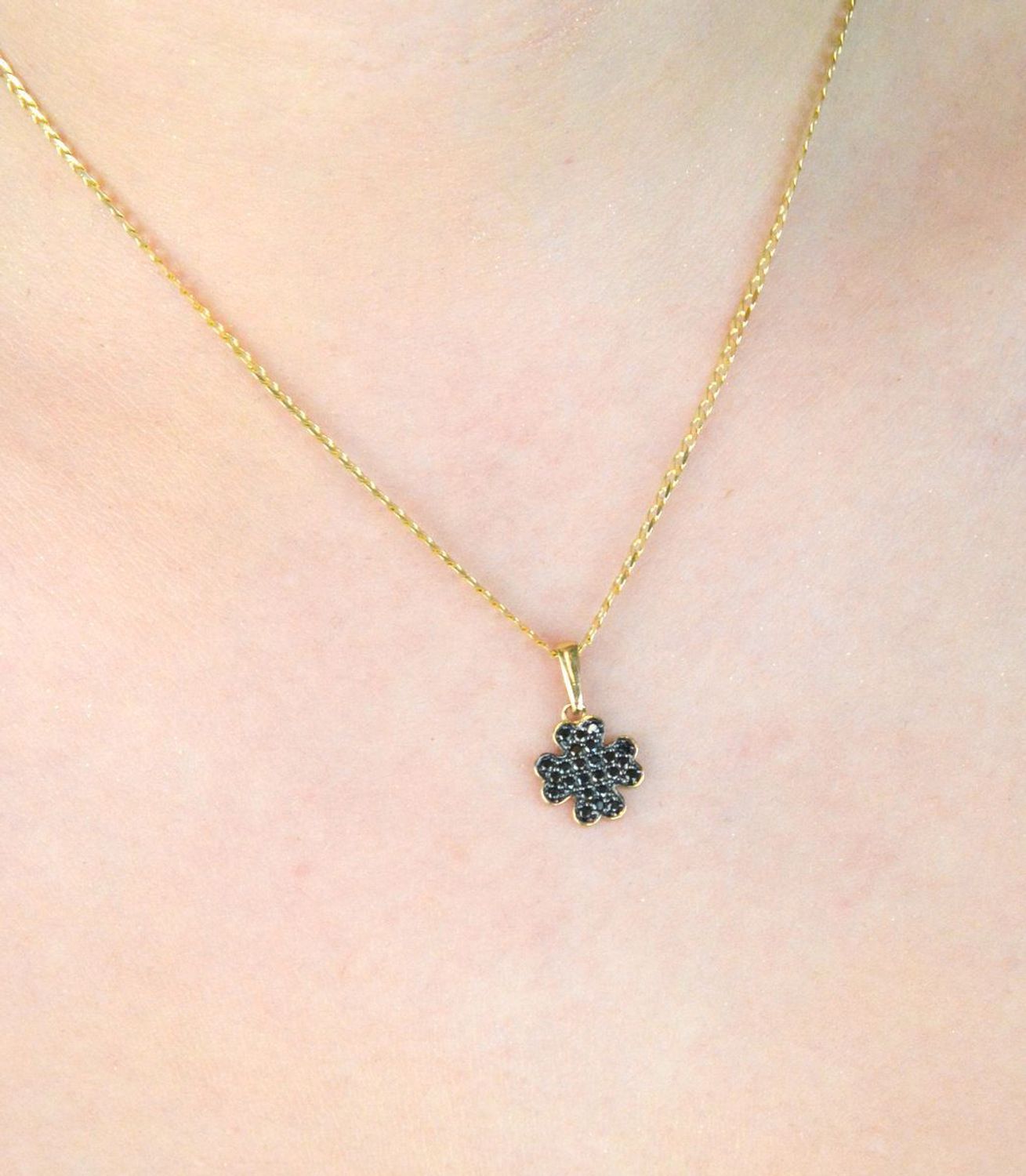 Złota zawieszka DIA-ZAW-13309-585 w kształcie koniczynki, zdobiona czarnymi cyrkoniami. Próba 585, waga 0,75 g, wymiary 1,7 × 1,0 cm. Stylowy symbol szczęścia – idealny na prezent!1.jpg