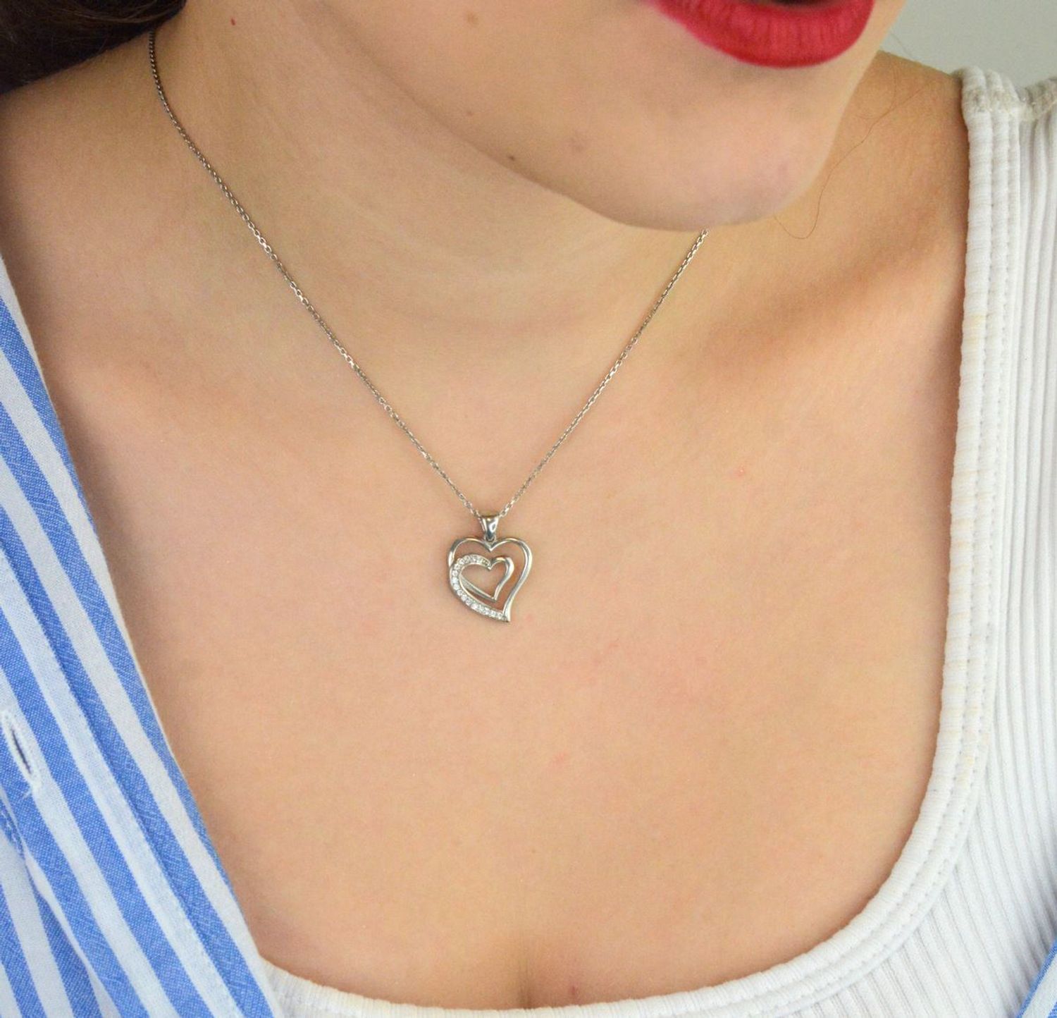 Zawieszka srebrna DIA-ZAW-13335-925 w kształcie dwóch serc, jedno ozdobione delikatną cyrkonią. Srebro próby 925, długość 2,0 cm, szerokość 1,5 cm, waga 1,80 g. Symboliczna i kobieca.1.jpg