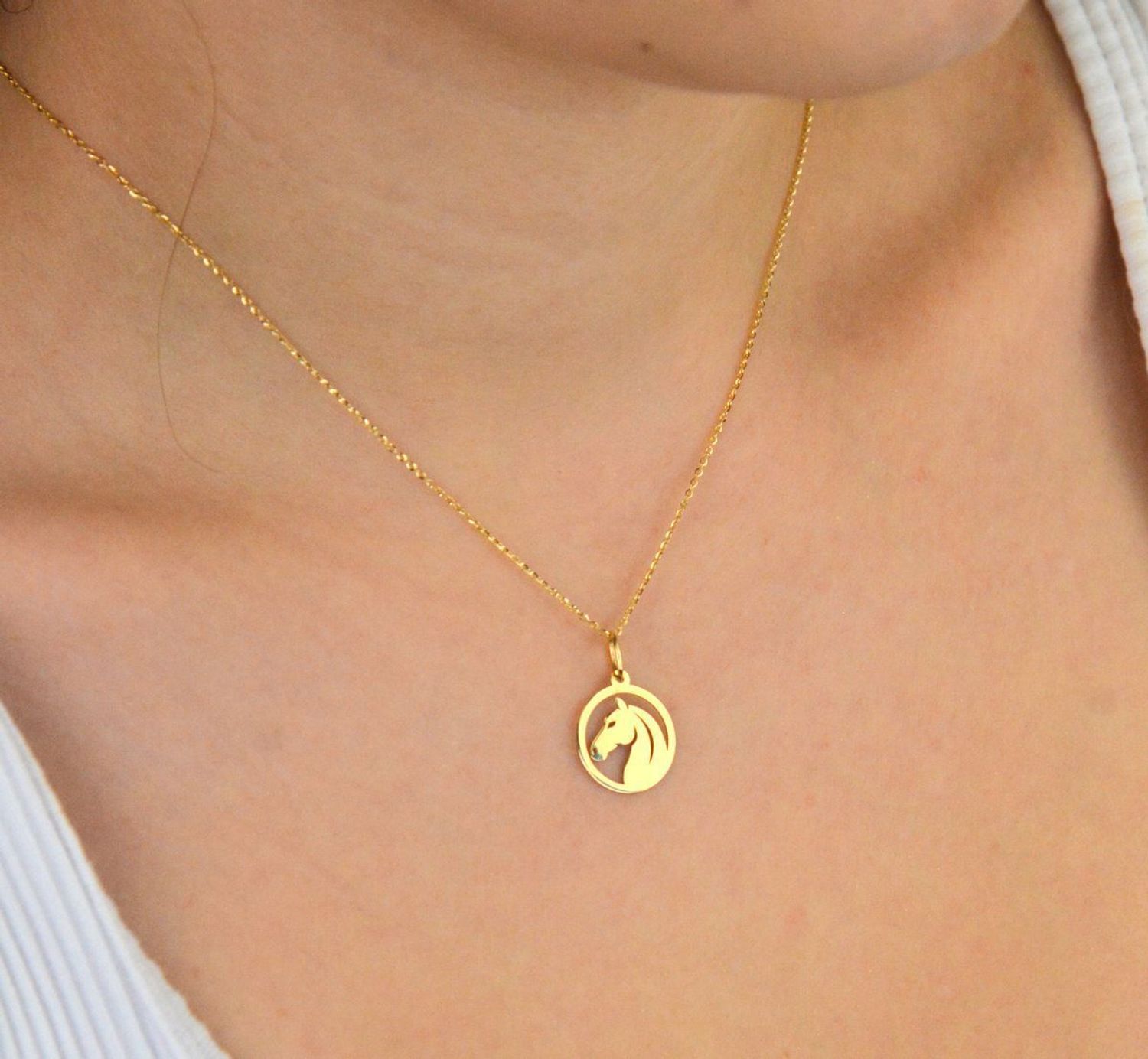 Stylowa zawieszka damska złota próby 585, model DIA-ZAW-13684-585. Okrągła z wizerunkiem głowy konia, wymiary 2,0 x 1,4 cm, waga 0,58 g. Idealna na prezent lub do codziennego noszenia.1.jpg