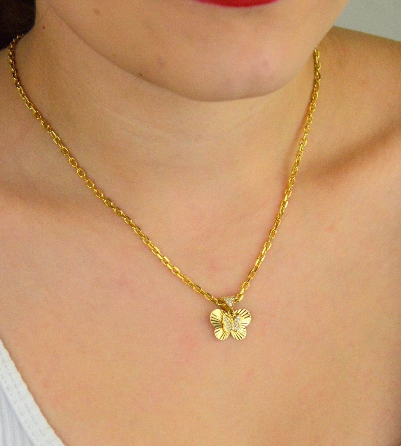 Zawieszka złota damska DIA-ZAW-13711-585 – motylek z wiszącym serduszkiem w cyrkonie. Wymiary 1,5 cm x 1,5 cm, waga 1,31 g. Delikatna i elegancka biżuteria idealna na prezent.1.jpg