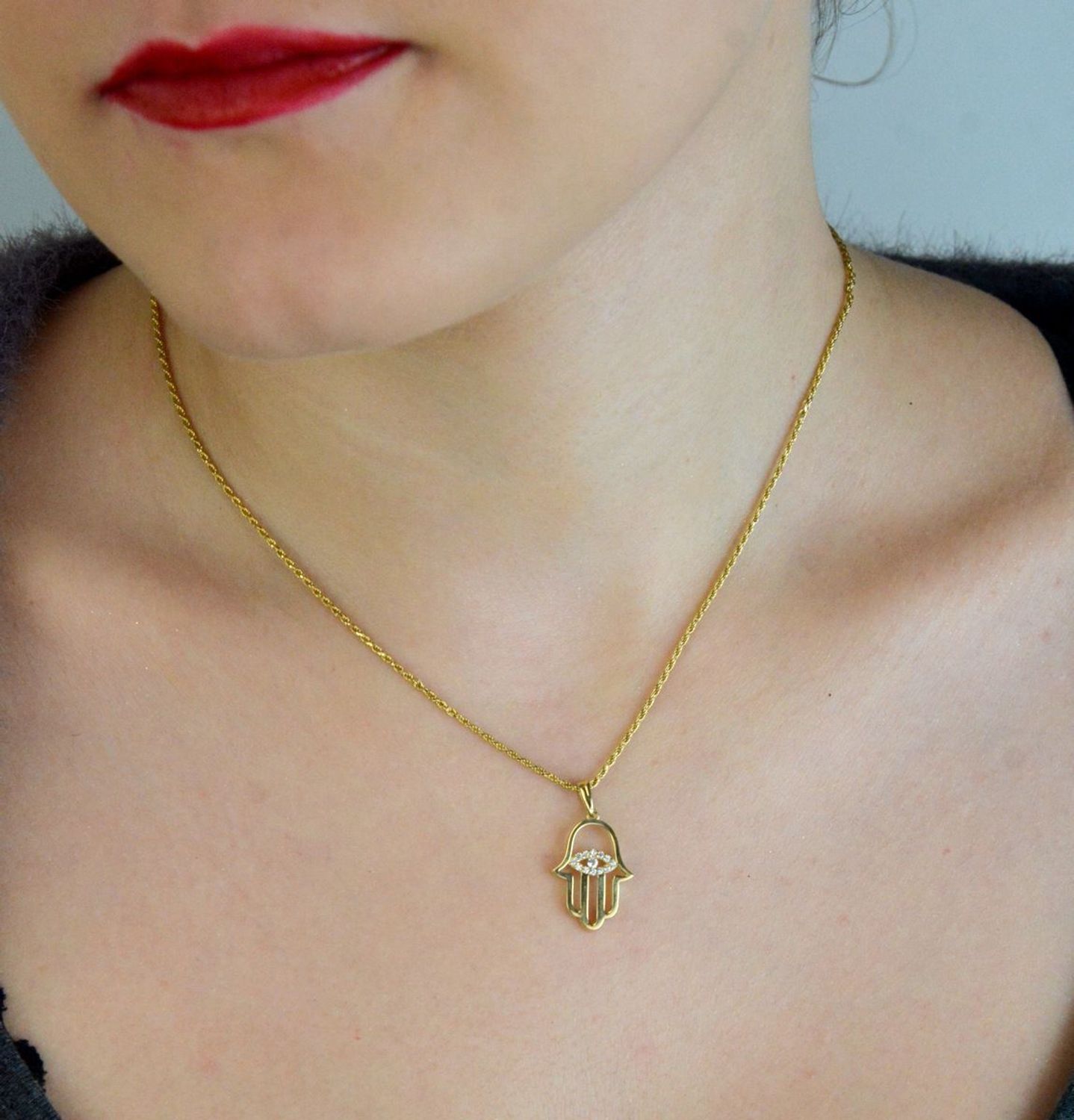 Elegancka zawieszka złota Ręka Fatimy z okiem próby 333, zdobiona białymi cyrkoniami. Wymiary 2,5×1,4 cm, waga 1,04 g. Idealny talizman i prezent.1.jpg