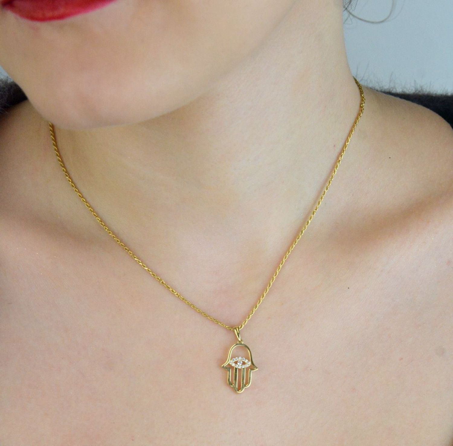 Elegancka zawieszka złota Ręka Fatimy z okiem próby 333, zdobiona białymi cyrkoniami. Wymiary 2,5×1,4 cm, waga 1,04 g. Idealny talizman i prezent.1.jpg