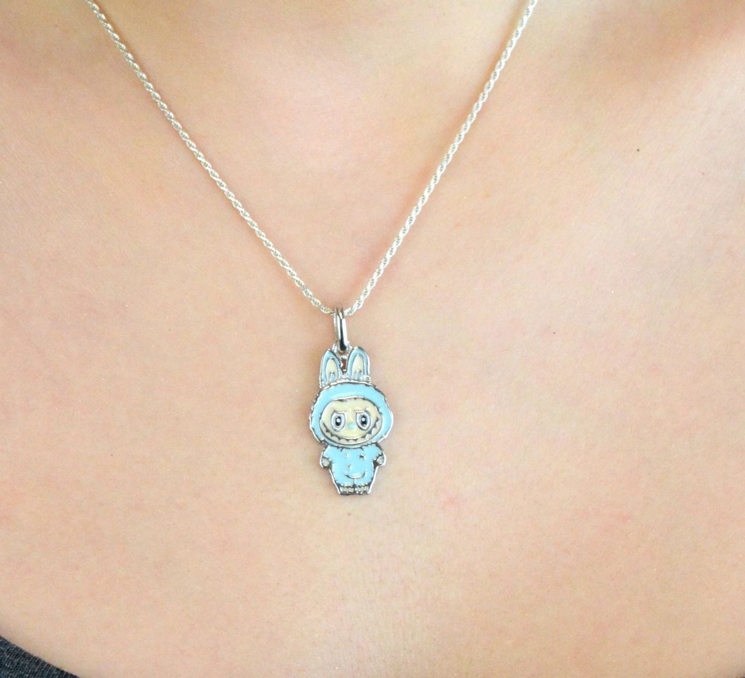 Zawieszka srebrna próby 925 w kształcie laleczki Labubu, zdobiona niebieską emalią. Model DIA-ZAW-13902-925, długość z oczkiem 3,0 cm, szerokość 1,3 cm, waga 3,00 g. Bajkowy i kolorowy prezent 1.jpg