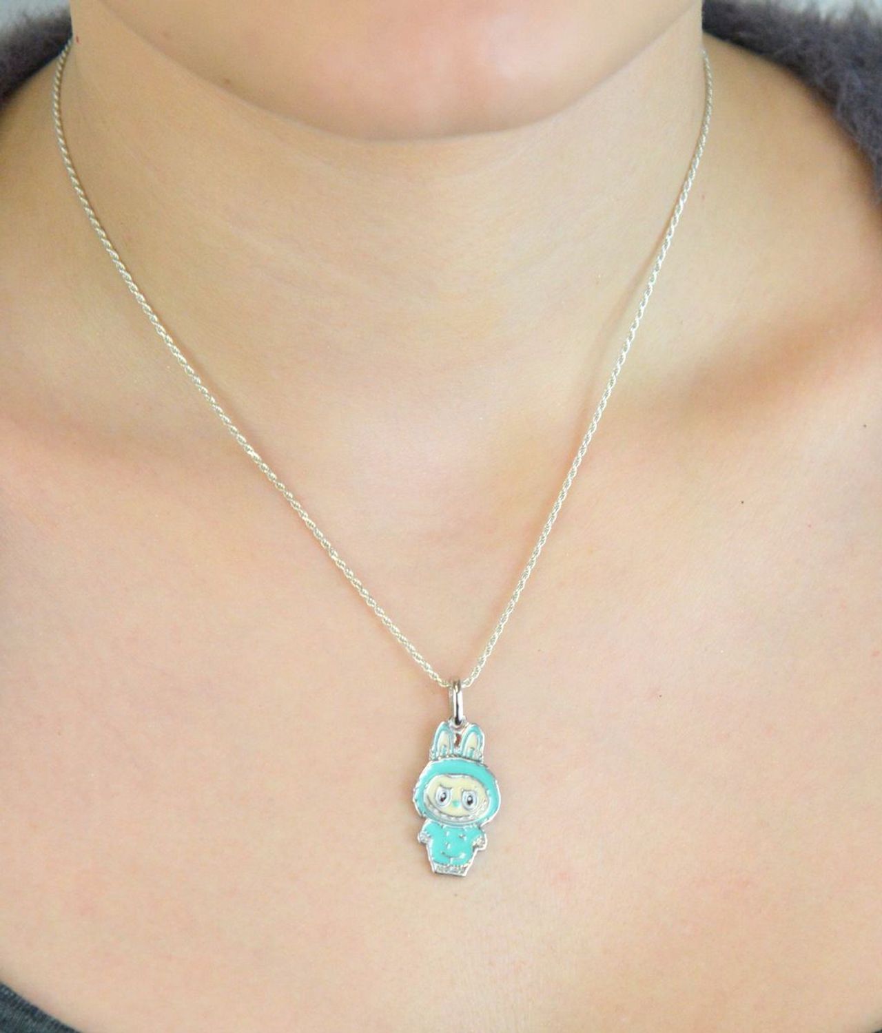 Zawieszka srebrna próby 925 w kształcie laleczki Labubu, zdobiona turkusową emalią. Model DIA-ZAW-13903-925, długość z oczkiem 3,0 cm, szerokość 1,3 cm, waga 3,00 g. Bajkowy i kolorowy prezent 1.jpg