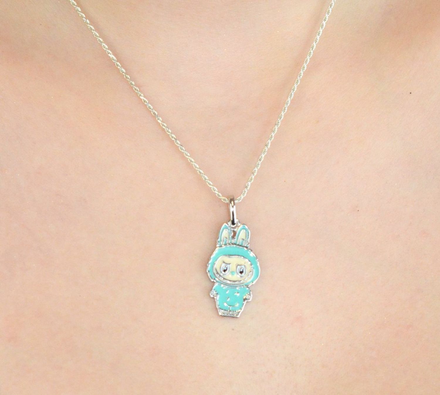 Zawieszka srebrna próby 925 w kształcie laleczki Labubu, zdobiona turkusową emalią. Model DIA-ZAW-13903-925, długość z oczkiem 3,0 cm, szerokość 1,3 cm, waga 3,00 g. Bajkowy i kolorowy prezent 1.jpg