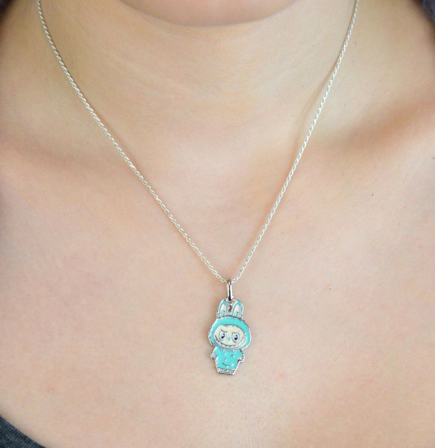 Zawieszka srebrna próby 925 w kształcie laleczki Labubu, zdobiona turkusową emalią. Model DIA-ZAW-13903-925, długość z oczkiem 3,0 cm, szerokość 1,3 cm, waga 3,00 g. Bajkowy i kolorowy prezent 1.jpg