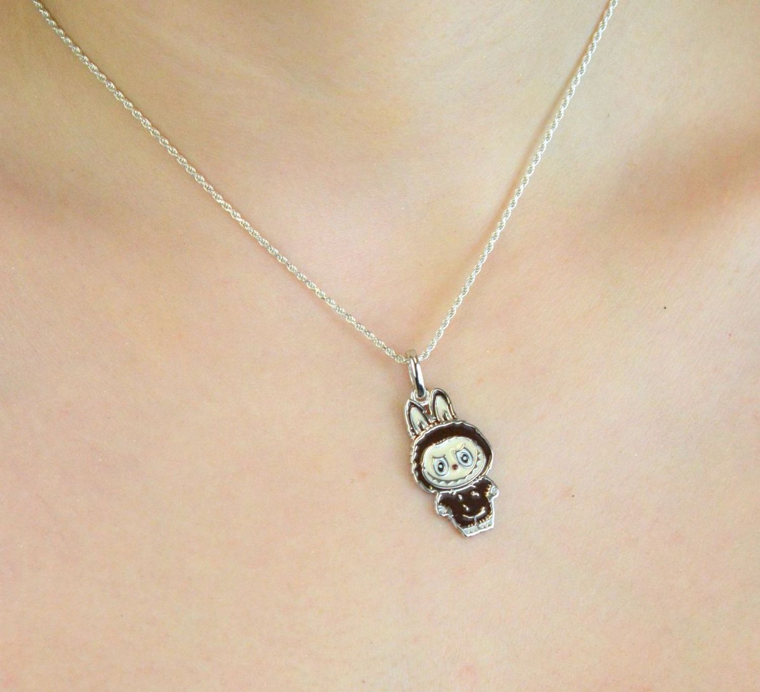 Zawieszka srebrna próby 925 w kształcie laleczki Labubu, zdobiona brązową emalią. Model DIA-ZAW-13906-925, długość 3,0 cm, szerokość 1,3 cm, waga 3,00 g. Bajkowy, kolorowy prezen1.jpg