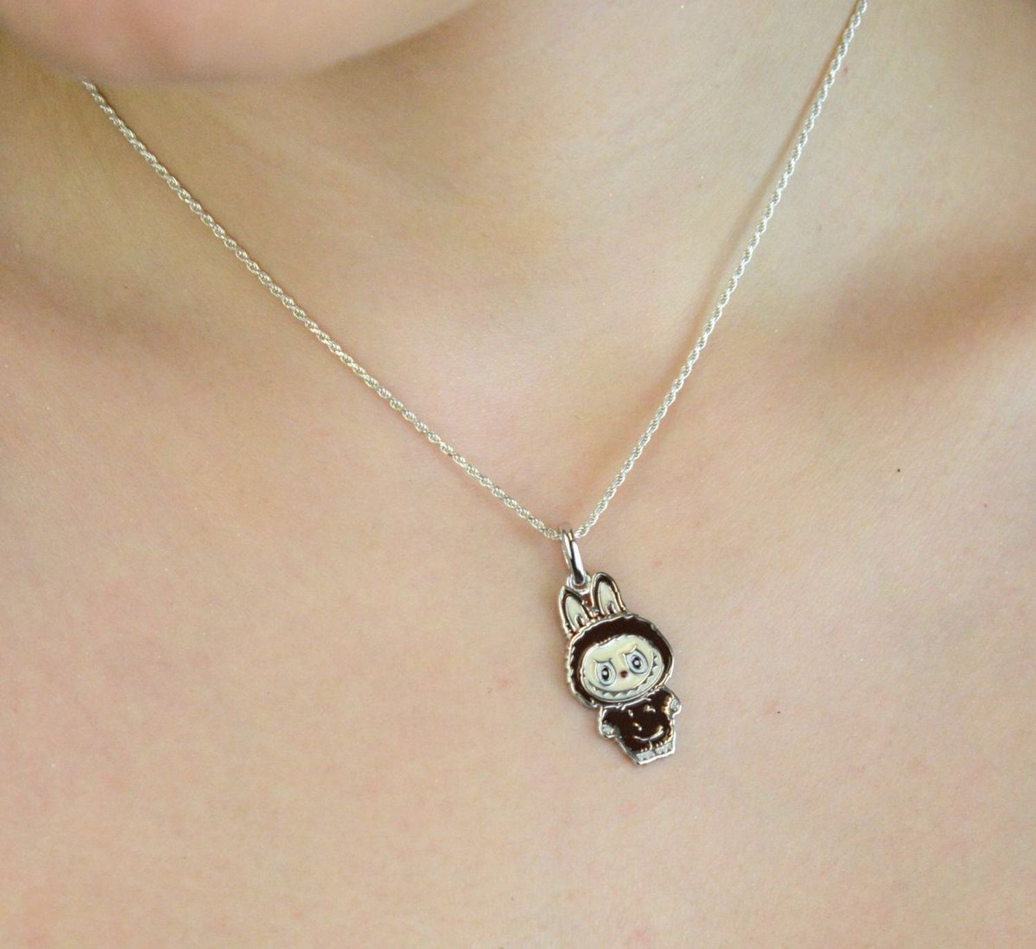 Zawieszka srebrna próby 925 w kształcie laleczki Labubu, zdobiona brązową emalią. Model DIA-ZAW-13906-925, długość 3,0 cm, szerokość 1,3 cm, waga 3,00 g. Bajkowy, kolorowy prezen1.jpg