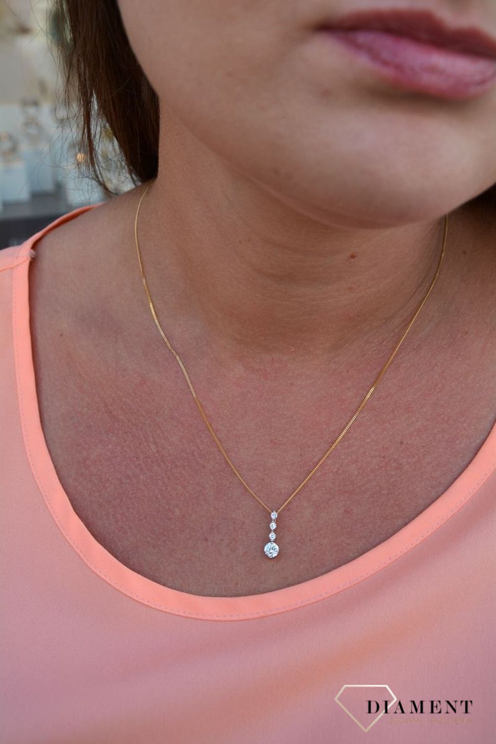 Zawieszka cyrkonie próby 333 DIA-ZAW-3047-333.  Złoty wisiorek o podłużnym kształcie z jedną większą cyrkonią oraz trzema mniejszymi. Wisiorek ten to idealny pomysł na prezent, którym wyjawimy swoje uczucia..jpg