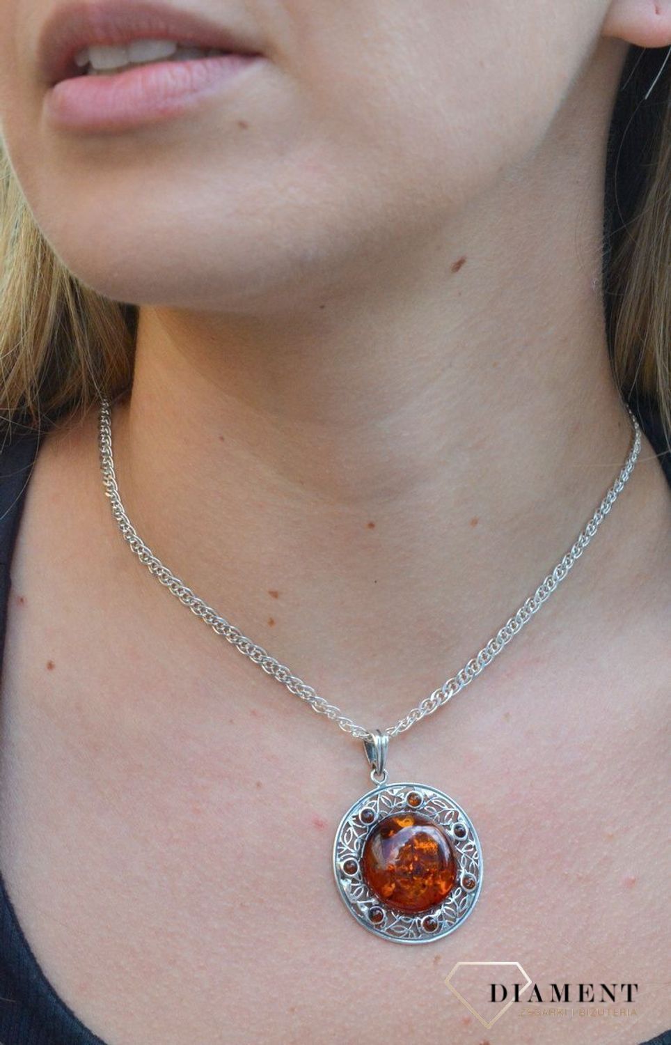 Zawieszka srebrna w okrągłym kształcie z bursztynem  DIA-ZAW-7122-925. Bursztyn wprawiono w najwyższej jakości srebro o próbie 925, kruszec od wielu setek lat symbolizujący głębię emocjonalną, duchowość i żeńską energię.jpg