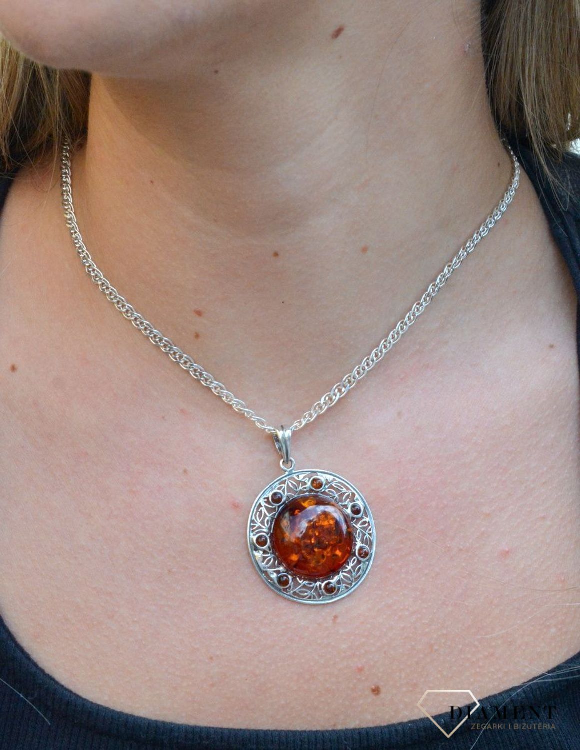 Zawieszka srebrna w okrągłym kształcie z bursztynem  DIA-ZAW-7122-925. Bursztyn wprawiono w najwyższej jakości srebro o próbie 925, kruszec od wielu setek lat symbolizujący głębię emocjonalną, duchowość i żeńską energię.jpg