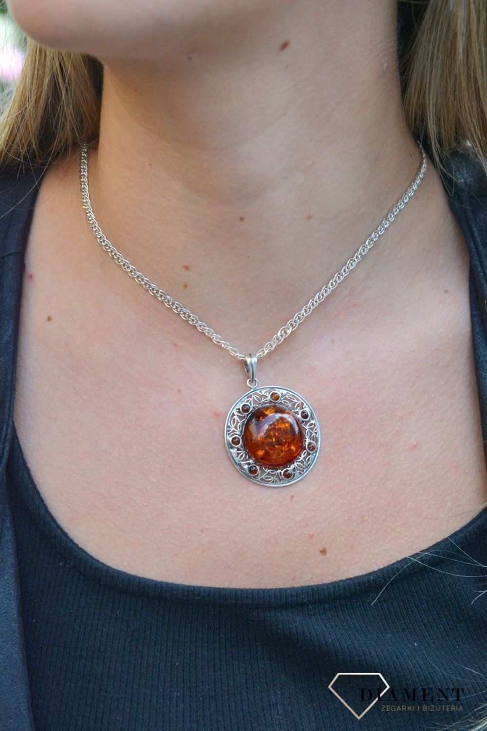 Zawieszka srebrna w okrągłym kształcie z bursztynem  DIA-ZAW-7122-925. Bursztyn wprawiono w najwyższej jakości srebro o próbie 925, kruszec od wielu setek lat symbolizujący głębię emocjonalną, duchowość i żeńską energię.jpg