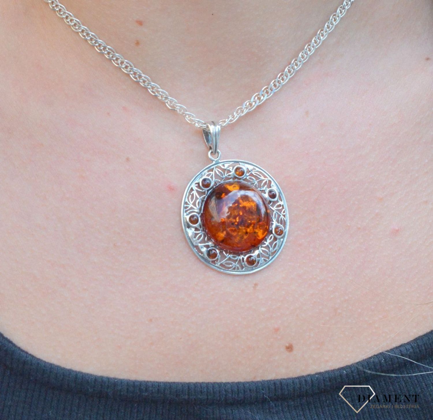 Zawieszka srebrna w okrągłym kształcie z bursztynem  DIA-ZAW-7122-925. Bursztyn wprawiono w najwyższej jakości srebro o próbie 925, kruszec od wielu setek lat symbolizujący głębię emocjonalną, duchowość i żeńską energię.jpg