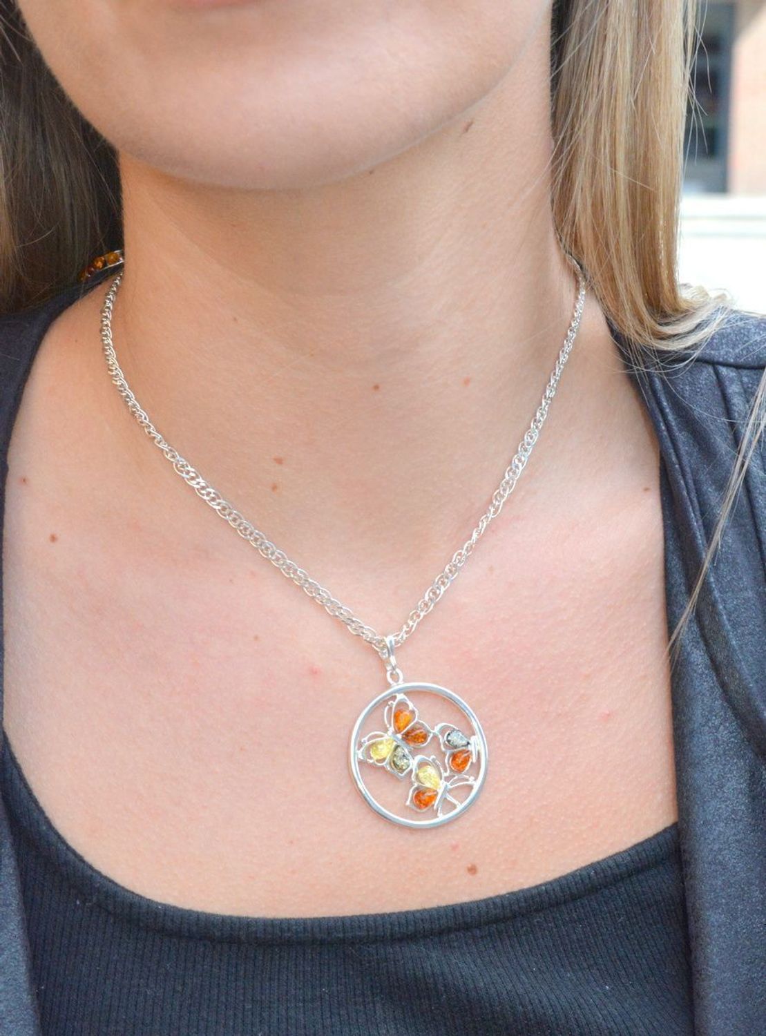 Zawieszka srebrna w kształcie koła z motylkami z bursztynu DIA-ZAW-7126-925. Bursztyn wprawiono w najwyższej jakości srebro o próbie 925, kruszec od wielu setek lat symbolizujący głębię emocjonalną, duchowość i żeńską energię.jpg