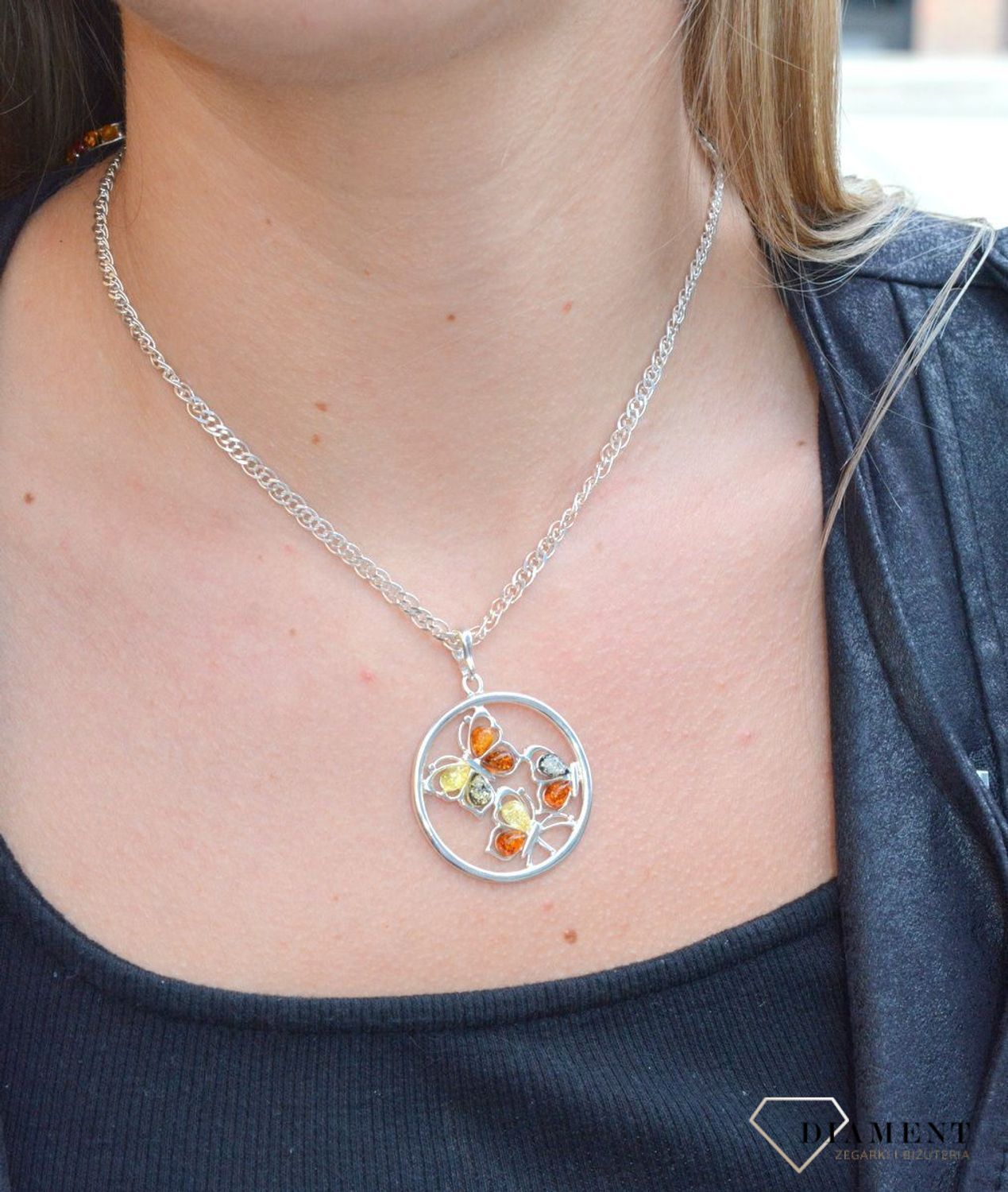 Zawieszka srebrna w kształcie koła z motylkami z bursztynu DIA-ZAW-7126-925. Bursztyn wprawiono w najwyższej jakości srebro o próbie 925, kruszec od wielu setek lat symbolizujący głębię emocjonalną, duchowość i żeńską energię.jpg