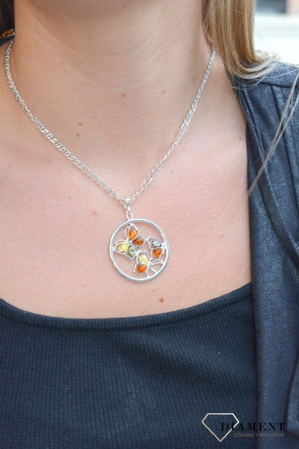 Zawieszka srebrna w kształcie koła z motylkami z bursztynu DIA-ZAW-7126-925. Bursztyn wprawiono w najwyższej jakości srebro o próbie 925, kruszec od wielu setek lat symbolizujący głębię emocjonalną, duchowość i żeńską energię.jpg