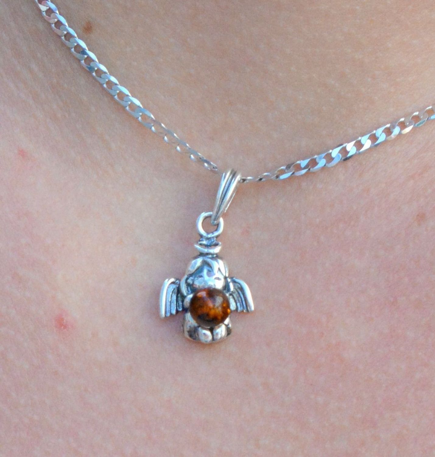 Srebrna zawieszka anioł z bursztynem DIA-ZAW-7134-925.  Elegancka zawieszka w kształcie aniołka z bursztynem. Zawieszka została wykonana z najwyższej jakości srebra próby 925.jpg