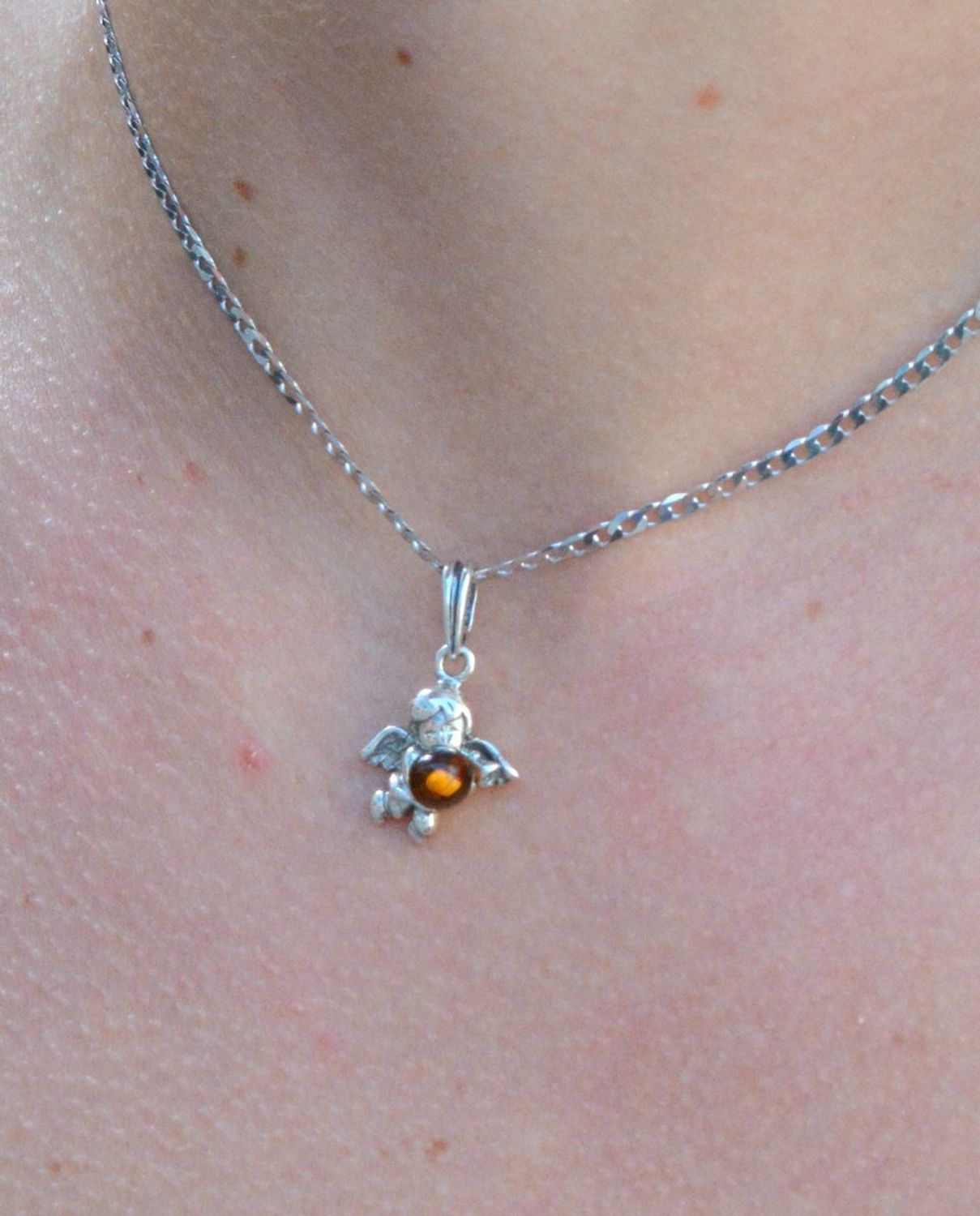 Zawieszka srebrna w kształcie aniołka z bursztynem DIA-ZAW-7135-925.  Bursztyn wprawiono w najwyższej jakości srebro o próbie 925, kruszec od wielu setek lat symbolizujący głębię emocjonalną, duchowość i żeńską energię.jpg