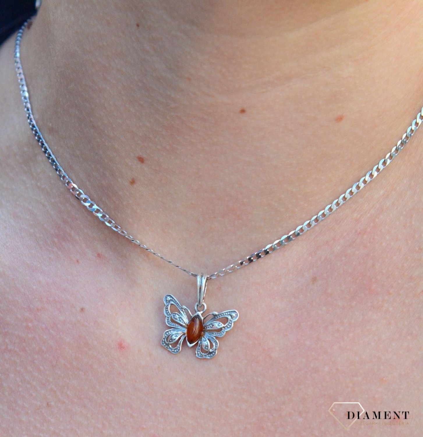 Zawieszka w kształcie motyla z bursztynem  DIA-ZAW-7137-925.  Bursztyn wprawiono w najwyższej jakości srebro o próbie 925, kruszec od wielu setek lat symbolizujący głębię emocjonalną, duchowość i żeńską energię.jpg