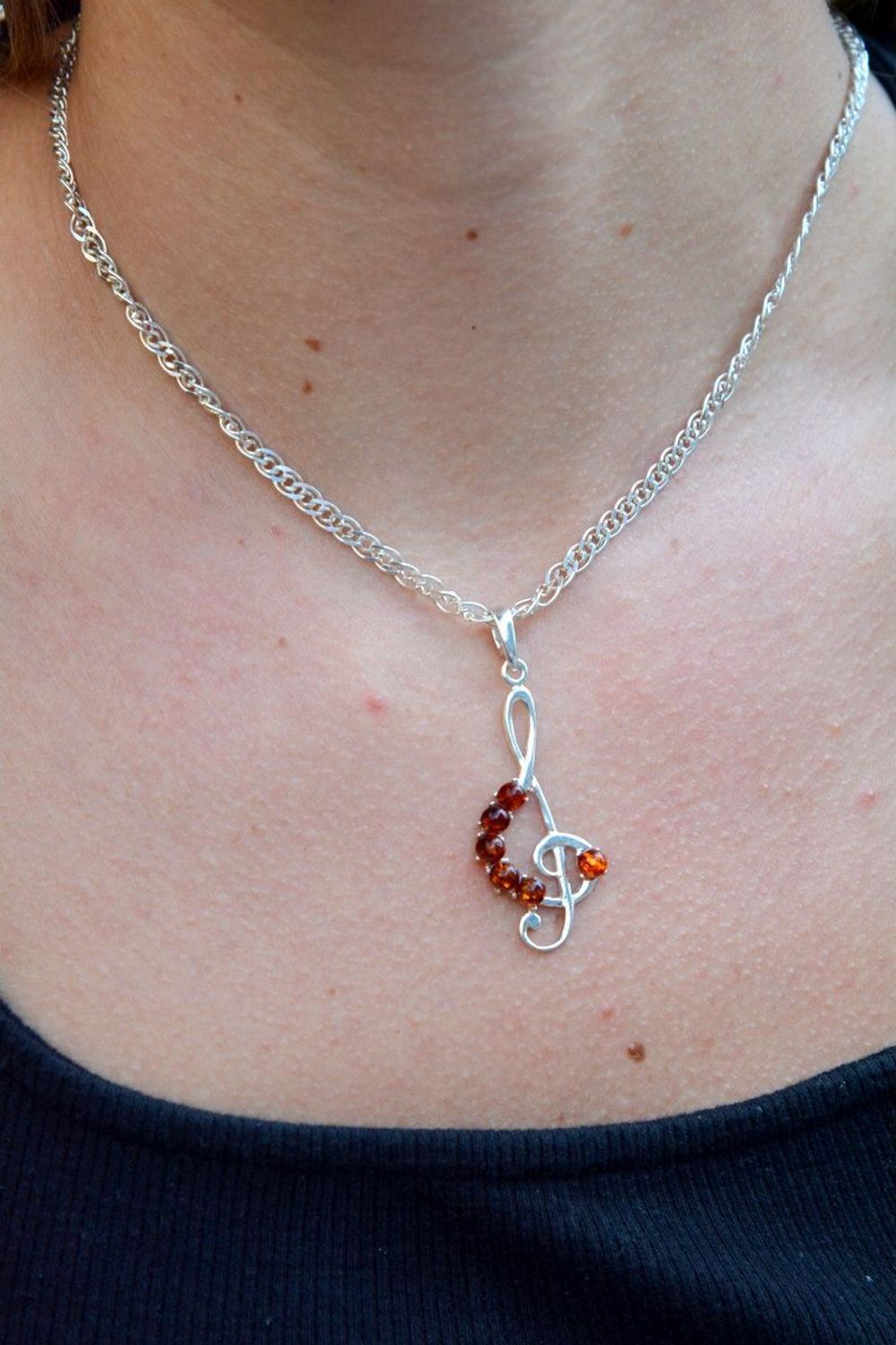 Zawieszka srebrna w kształcie klucza wiolinowego z bursztynem DIA-ZAW-7139-92. Bursztyn wprawiono w najwyższej jakości srebro o próbie 925, kruszec od wielu setek lat symbolizujący głębię emocjonalną, duchowość i żeńską energ.jpg