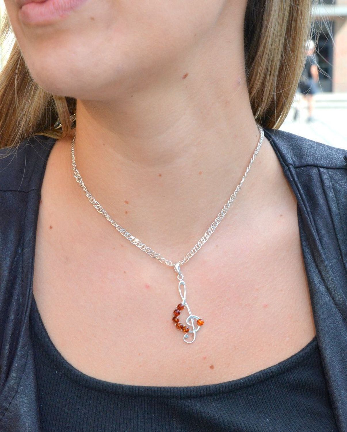 Zawieszka srebrna w kształcie klucza wiolinowego z bursztynem DIA-ZAW-7139-92. Bursztyn wprawiono w najwyższej jakości srebro o próbie 925, kruszec od wielu setek lat symbolizujący głębię emocjonalną, duchowość i żeńską energ.jpg