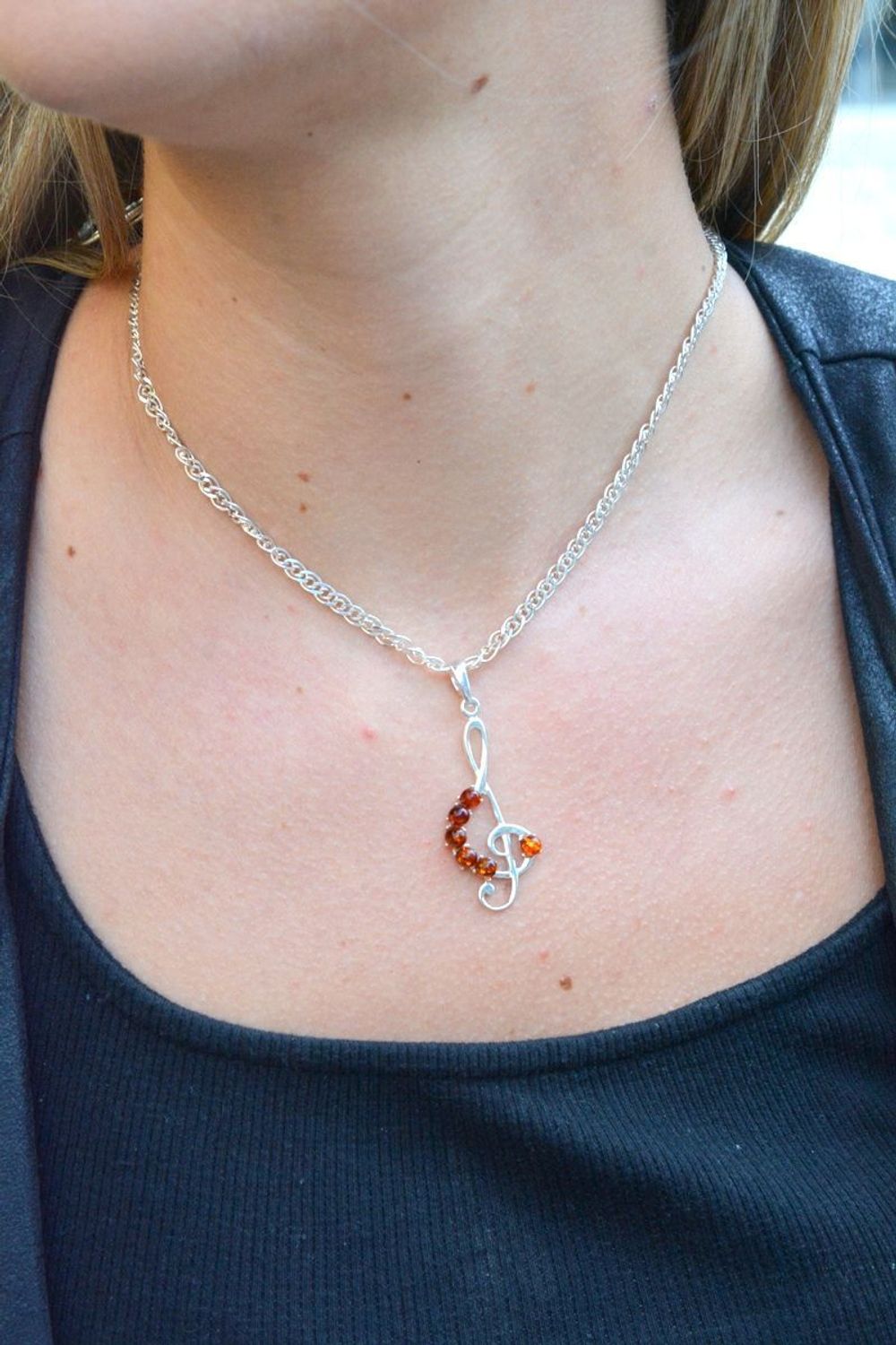 Zawieszka srebrna w kształcie klucza wiolinowego z bursztynem DIA-ZAW-7139-92. Bursztyn wprawiono w najwyższej jakości srebro o próbie 925, kruszec od wielu setek lat symbolizujący głębię emocjonalną, duchowość i żeńską energ.jpg