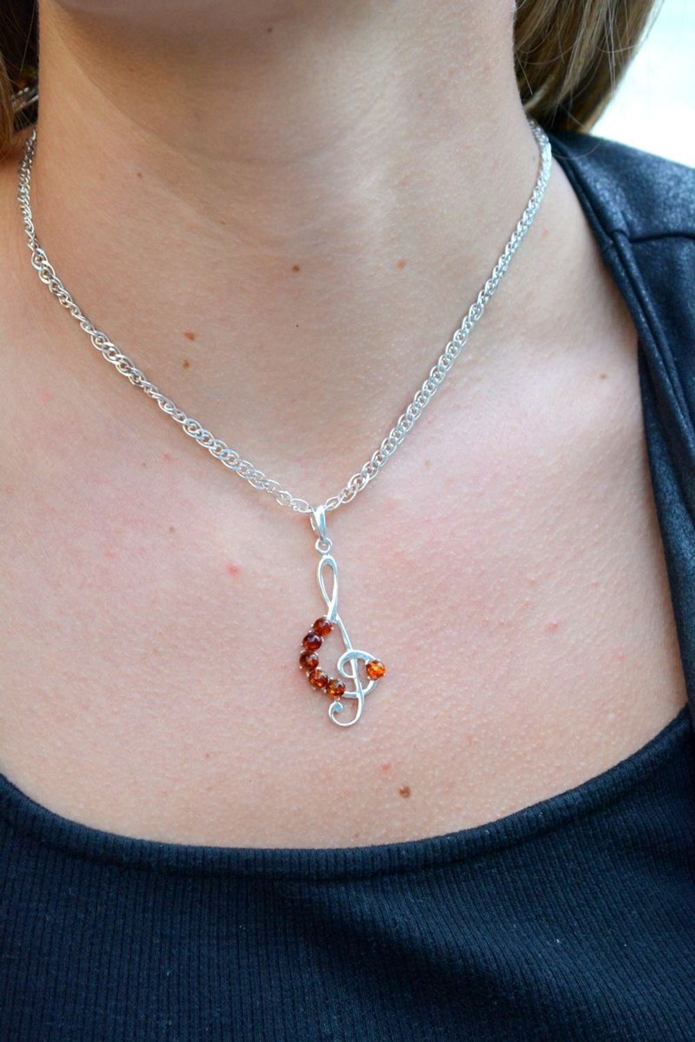 Zawieszka srebrna w kształcie klucza wiolinowego z bursztynem DIA-ZAW-7139-92. Bursztyn wprawiono w najwyższej jakości srebro o próbie 925, kruszec od wielu setek lat symbolizujący głębię emocjonalną, duchowość i żeńską energ.jpg