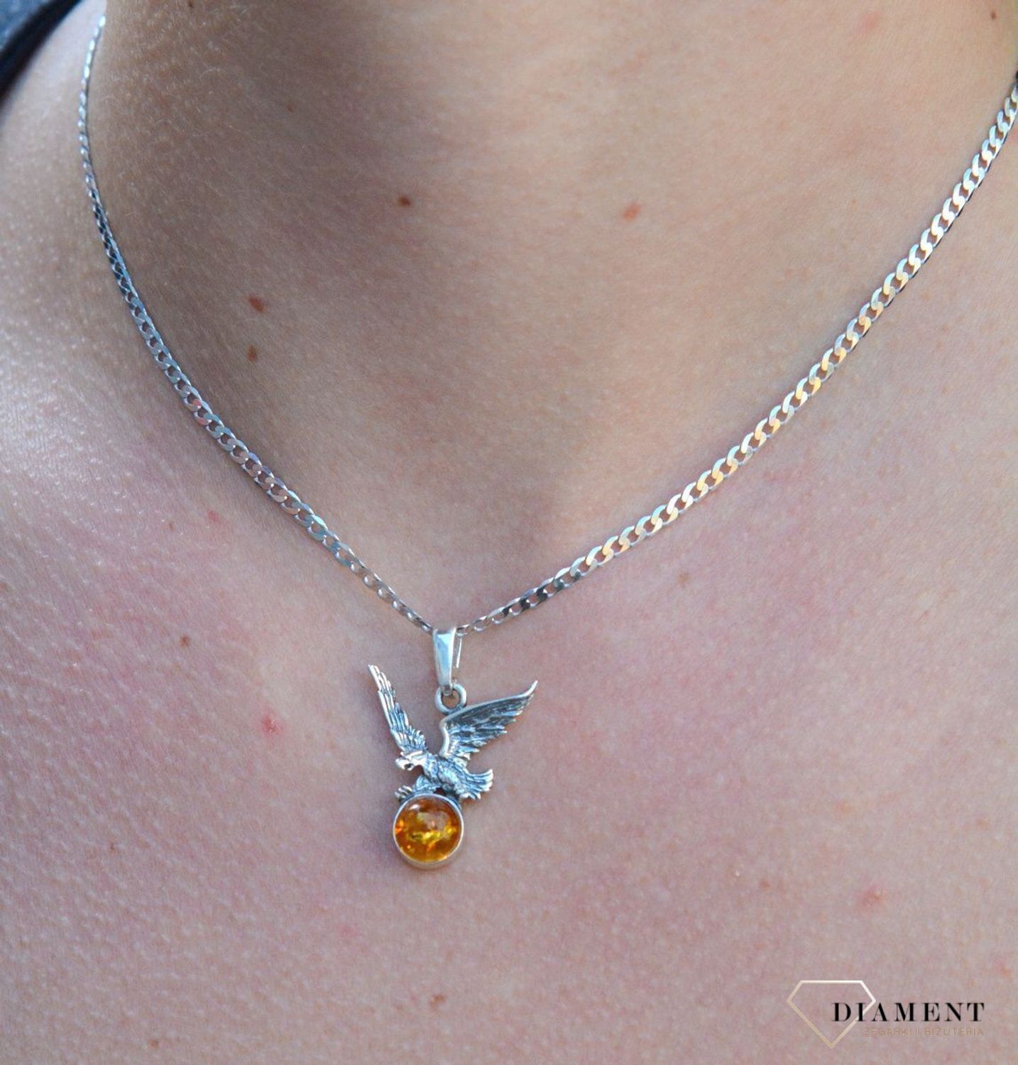 Zawieszka srebrna orzeł z bursztynem DIA-ZAW-7140-925. Bursztyn wprawiono w najwyższej jakości srebro o próbie 925, kruszec od wielu setek lat symbolizujący głębię emocjonalną, duchowość i żeńską energię.jpg