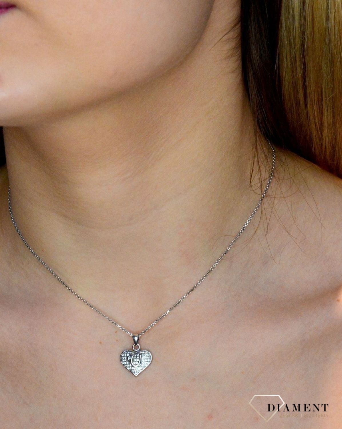 Srebrna zawieszka literka U w serduszku z cyrkoniami DIA-ZAW-8752-U-925. Zawieszka w kształcie serduszka z literką U w środku wykonana z najwyższej próby srebra. Srebrna zawieszka w kształcie serca wykonana została w próby 925.jpg