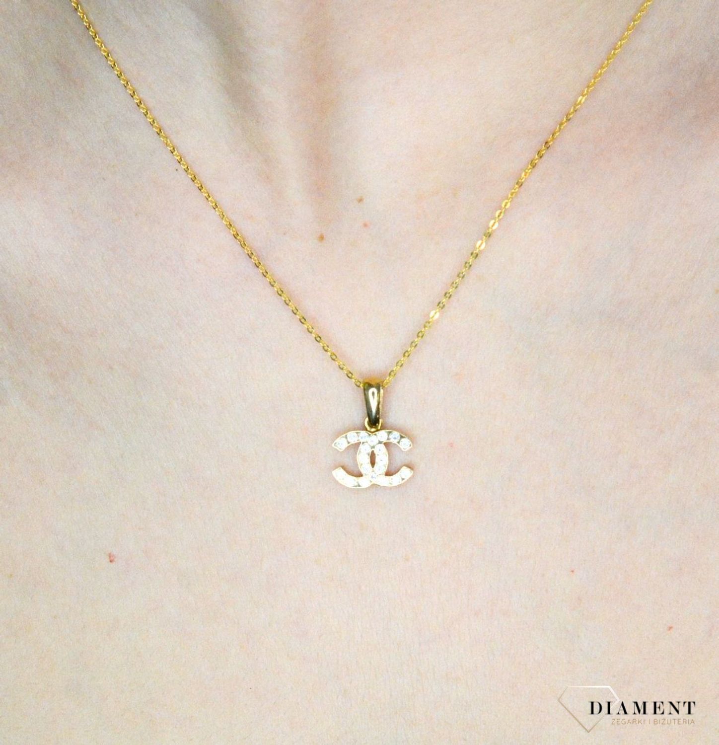 Złota zawieszka 585 o wzorze chanel z cyrkoniami DIA-ZAW-9146-585. Piękny, złoty wisiorek o ciekawym i modnym wzorze chanel misia wykonana z żółtego 14-karatowego złota z wysokiej próby 585. Ta zawieszka będzie idealną ozdobą.jpg