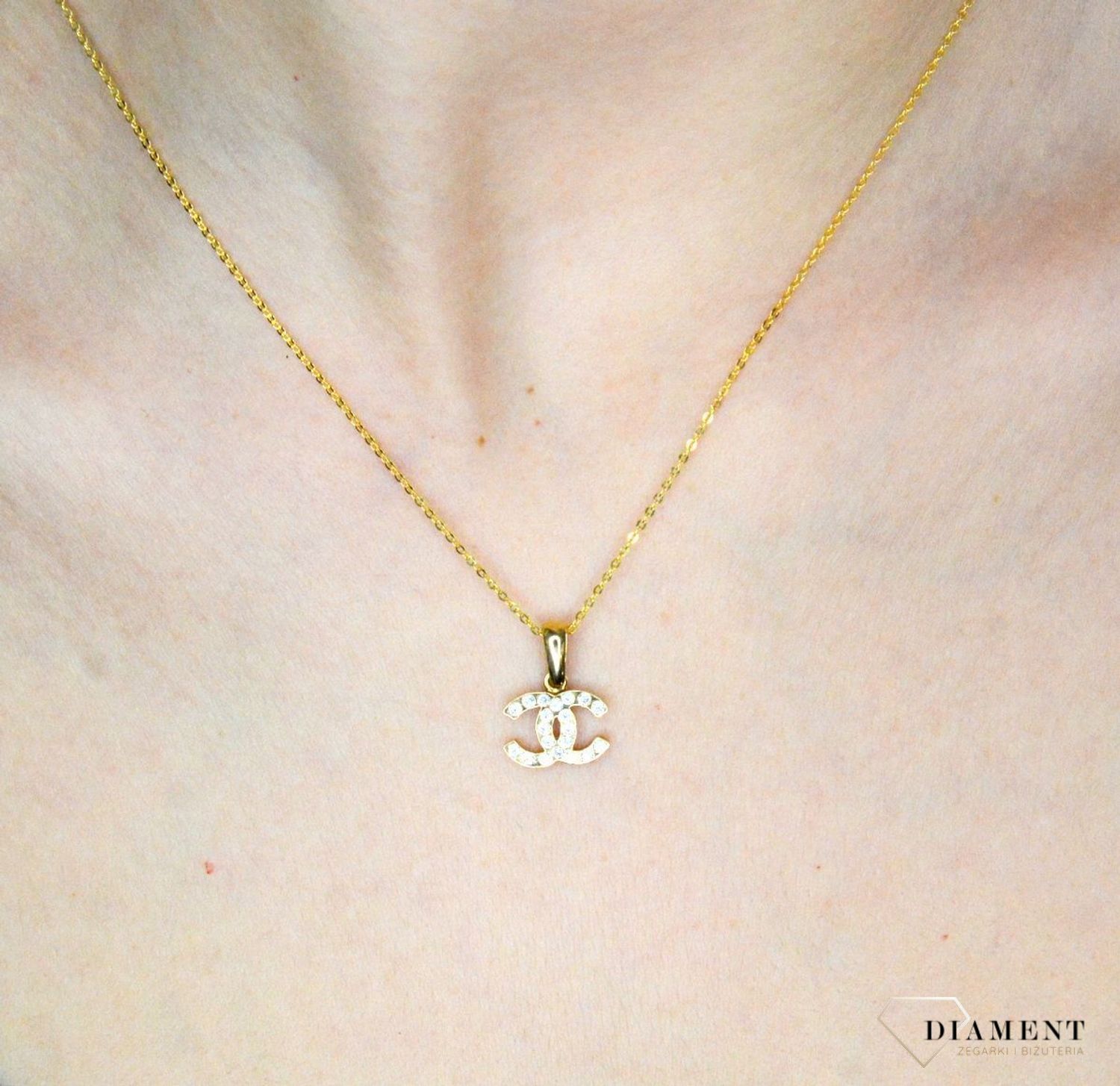 Złota zawieszka 585 o wzorze chanel z cyrkoniami DIA-ZAW-9146-585. Piękny, złoty wisiorek o ciekawym i modnym wzorze chanel misia wykonana z żółtego 14-karatowego złota z wysokiej próby 585. Ta zawieszka będzie idealną ozdobą.jpg