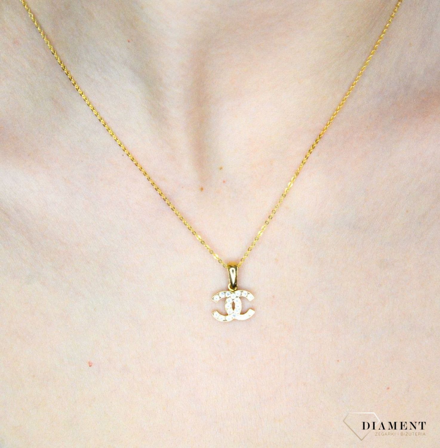 Złota zawieszka 585 o wzorze chanel z cyrkoniami DIA-ZAW-9146-585. Piękny, złoty wisiorek o ciekawym i modnym wzorze chanel misia wykonana z żółtego 14-karatowego złota z wysokiej próby 585. Ta zawieszka będzie idealną ozdobą.jpg