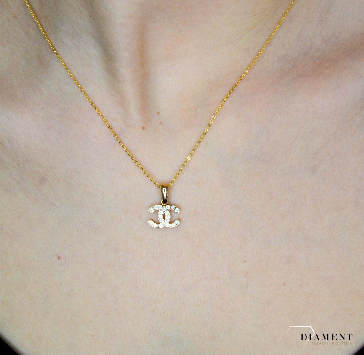 Złota zawieszka 585 o wzorze chanel z cyrkoniami DIA-ZAW-9146-585. Piękny, złoty wisiorek o ciekawym i modnym wzorze chanel misia wykonana z żółtego 14-karatowego złota z wysokiej próby 585. Ta zawieszka będzie idealną ozdobą.jpg