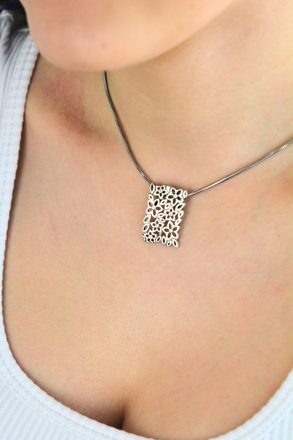 Elegancka srebrna zawieszka damska w kształcie prostokąta, zdobiona drobnymi kwiatkami i cyrkoniami. Wykonana ze srebra próby 925 o wadze 2,97 g. Idealna na prezent.1.jpg