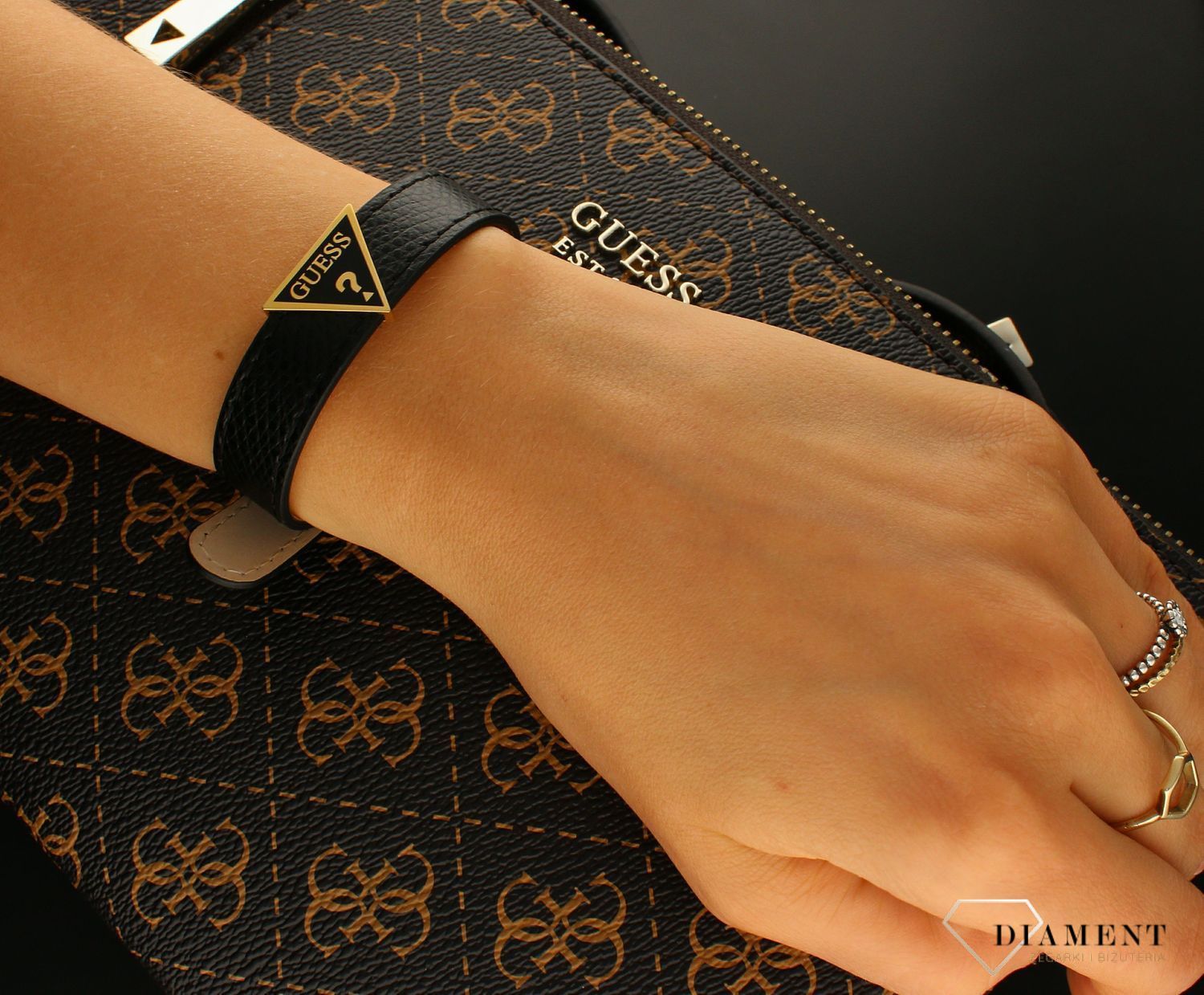 Bransoletka GUESS czarna skóra z logiem JUBB01495JWYGBK. Bransoletka GUESS skórzany pasek ze stalowym zapięciem w kolorze złotym. Bransoletka  Guess w kolorze czarnym ze złotym elementem ozdobnym.webp