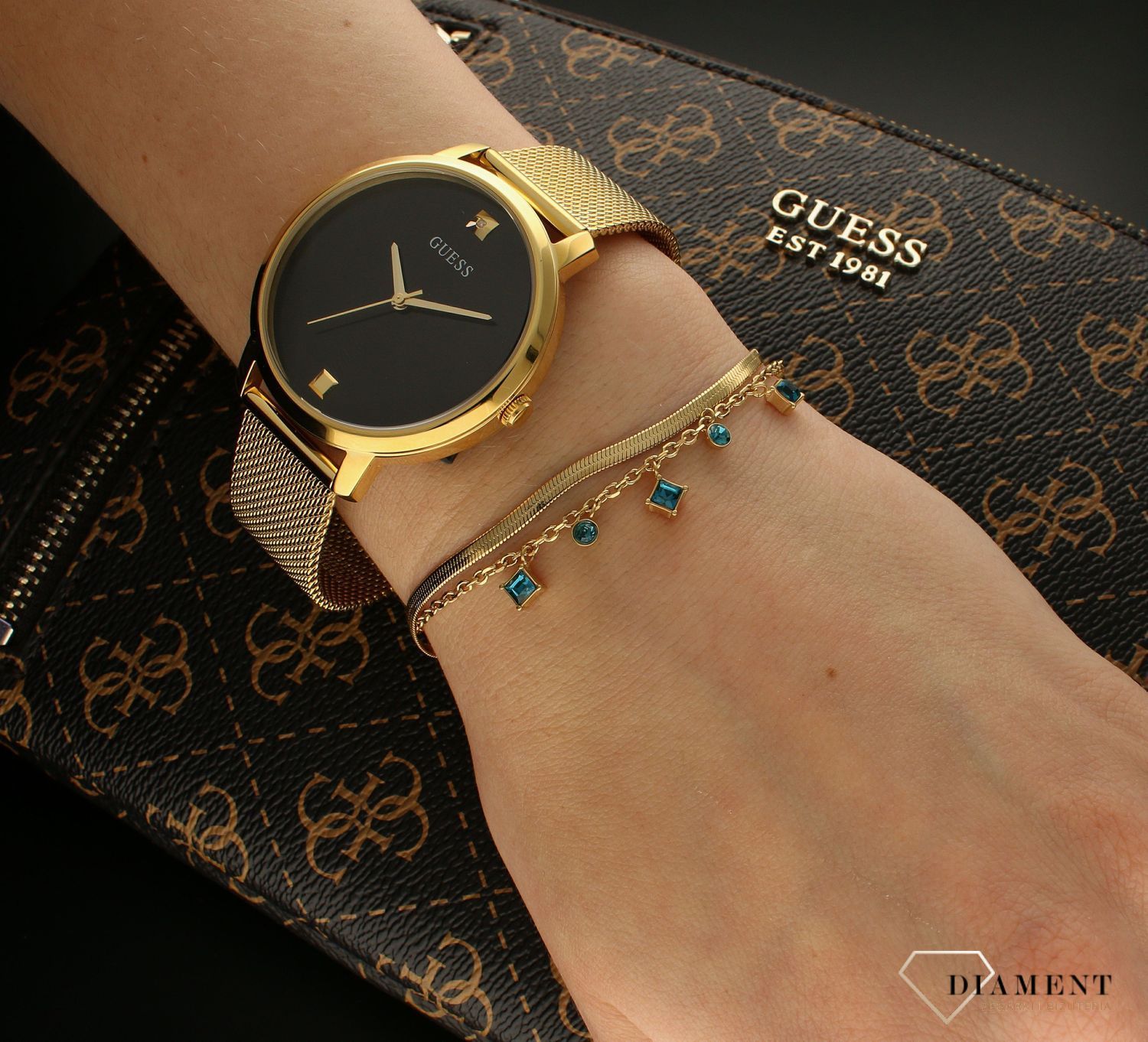 Bransoletka damska Guess z niebieskimi cyrkoniami JUBB03068JWYGAQS. Bransoletka damska Guess w złotym kolorze z wiszącymi elementami ozdobnymi w niebieskim kolorze. Stalowa bransoletka w kolorze złotym z cyrkoniami. Bransoletka Guess na pre.jpg