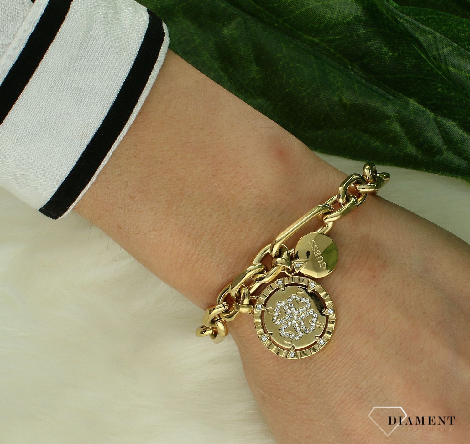 Bransoletka GUESS stalowa w kolorze złotym z elementami wiszącymi i koniczynką ozdobioną cyrkoniami JUBB04037JWYGS.png