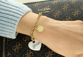Bransoletka Guess z pozłacanej stali i zawieszką serce z białej emalii. Długość 18 cm + 3 cm. Elegancka, romantyczna biżuteria z logo Guess. Model JUBB05149JWYGWHS. Bransoletka damska Guess z białym sercem i poz (4).jpg