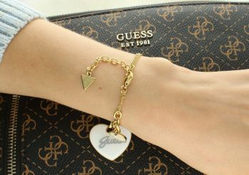 Bransoletka Guess z pozłacanej stali i zawieszką serce z białej emalii. Długość 18 cm + 3 cm. Elegancka, romantyczna biżuteria z logo Guess. Model JUBB05149JWYGWHS. Bransoletka damska Guess z białym sercem i pozła (1).jpg