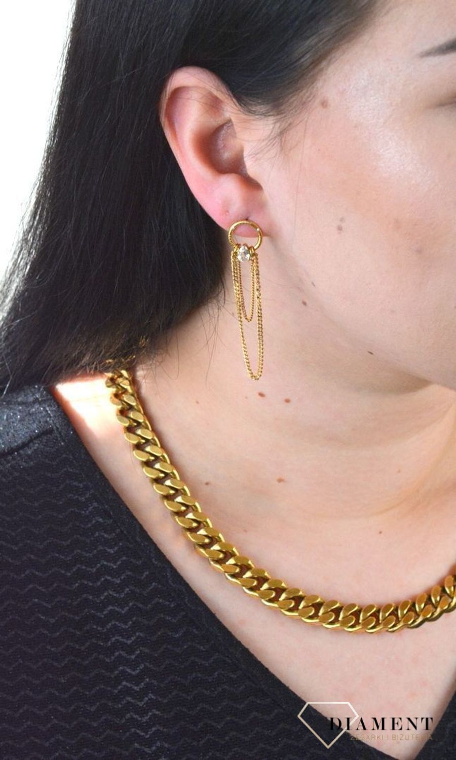 Stalowe kolczyki wiszące z logo marki GUESS w kolorze złotym. Kolczyki składają się z łańcuszków pancerki do którego dołączony jest kryształka..jpg