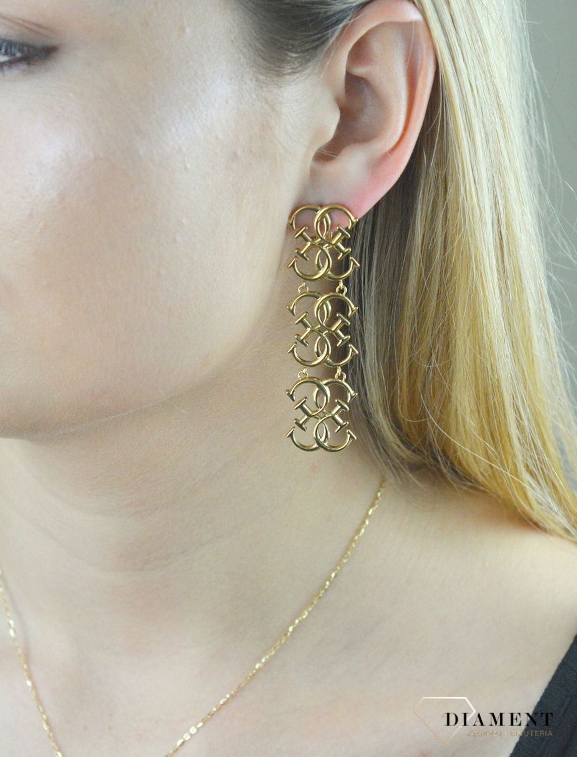 Kolczyki stalowe GUESS w kolorze złota JUBE01478JWYG.  Stalowe kolczyki wiszące z logo marki GUESS w kolorze złotym. Kolczyki składają się z trzech elementów w kształcie logo Guess. Wiszące kolczyki Guess z wygodnym zapięc.jpg