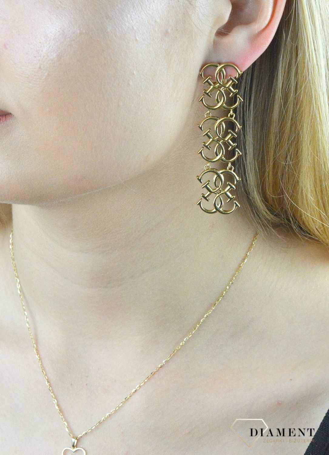 Kolczyki stalowe GUESS w kolorze złota JUBE01478JWYG.  Stalowe kolczyki wiszące z logo marki GUESS w kolorze złotym. Kolczyki składają się z trzech elementów w kształcie logo Guess. Wiszące kolczyki Guess z wygodnym zapięc.jpg