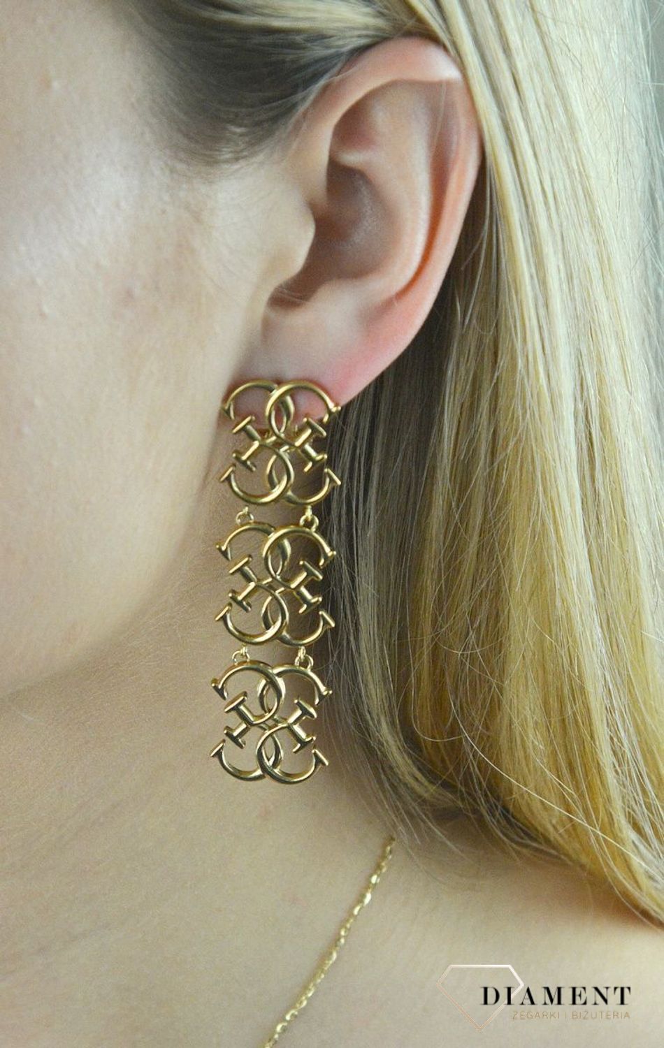 Kolczyki stalowe GUESS w kolorze złota JUBE01478JWYG.  Stalowe kolczyki wiszące z logo marki GUESS w kolorze złotym. Kolczyki składają się z trzech elementów w kształcie logo Guess. Wiszące kolczyki Guess z wygodnym zapięc.jpg
