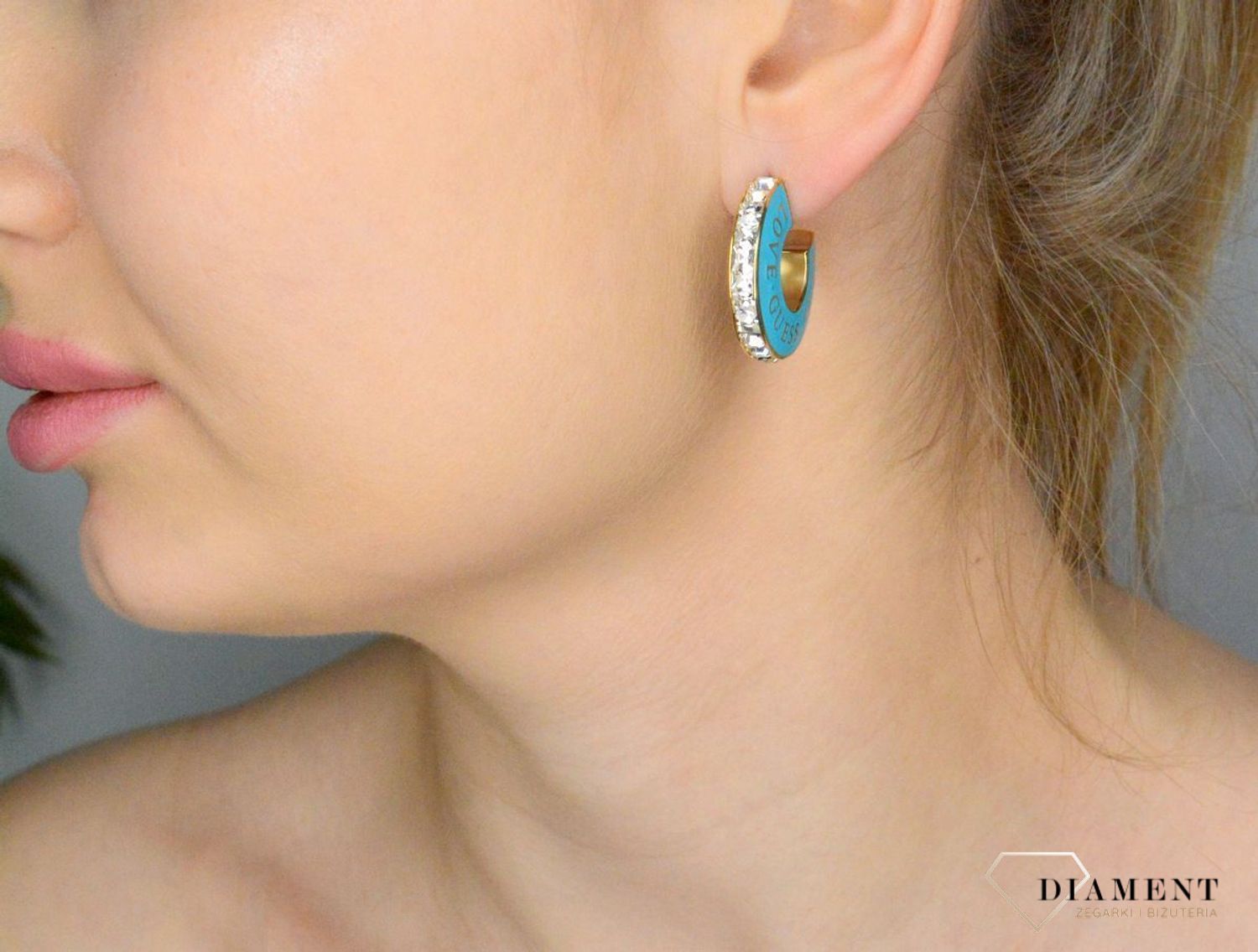 Kolczyki GUESS z emalią w kolorze turkusowym JUBE04083JWYGTQT-U. Kolczyki wykonane ze stali w kolorze złotym z emalią w kolorze turkusowym z logo marki GUESS (1).jpg