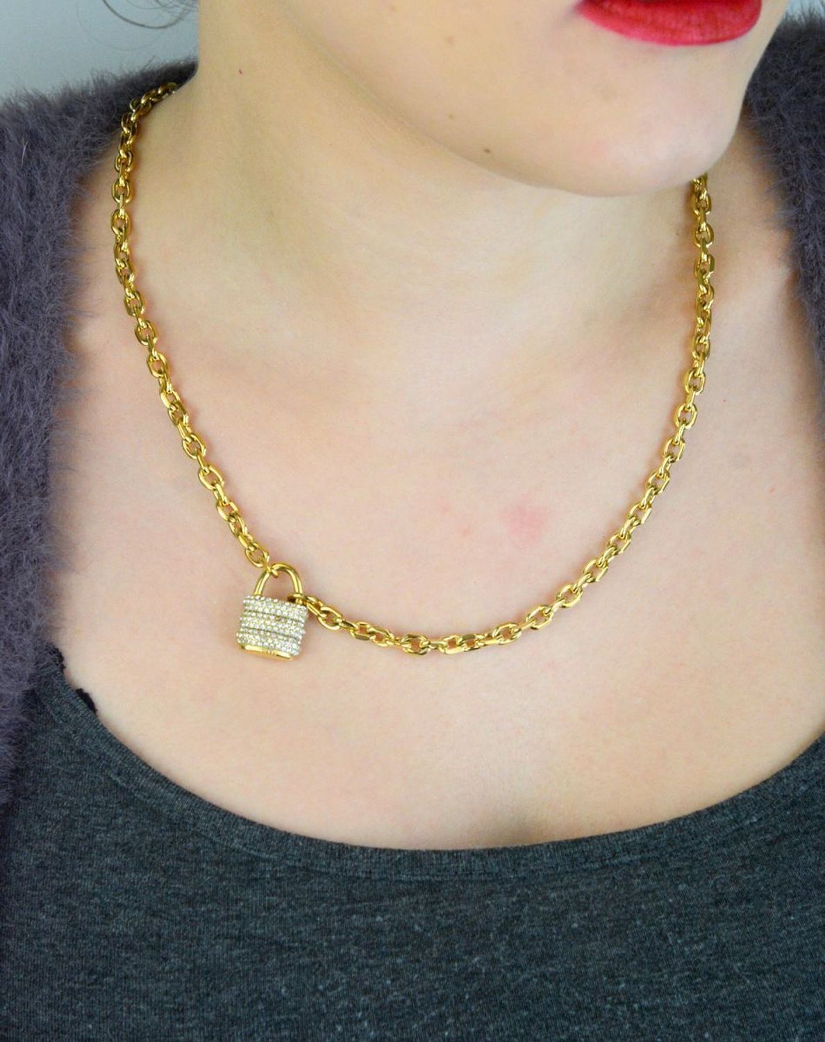 Pozłacany naszyjnik GUESS JUBN05415JWYGTU z zawieszką w kształcie kłódki i zdobieniem z kamieni. Wykonany ze stali szlachetnej, łączy elegancję i trwałość. Idealny na co dzień i wyjątkowe 1.jpg