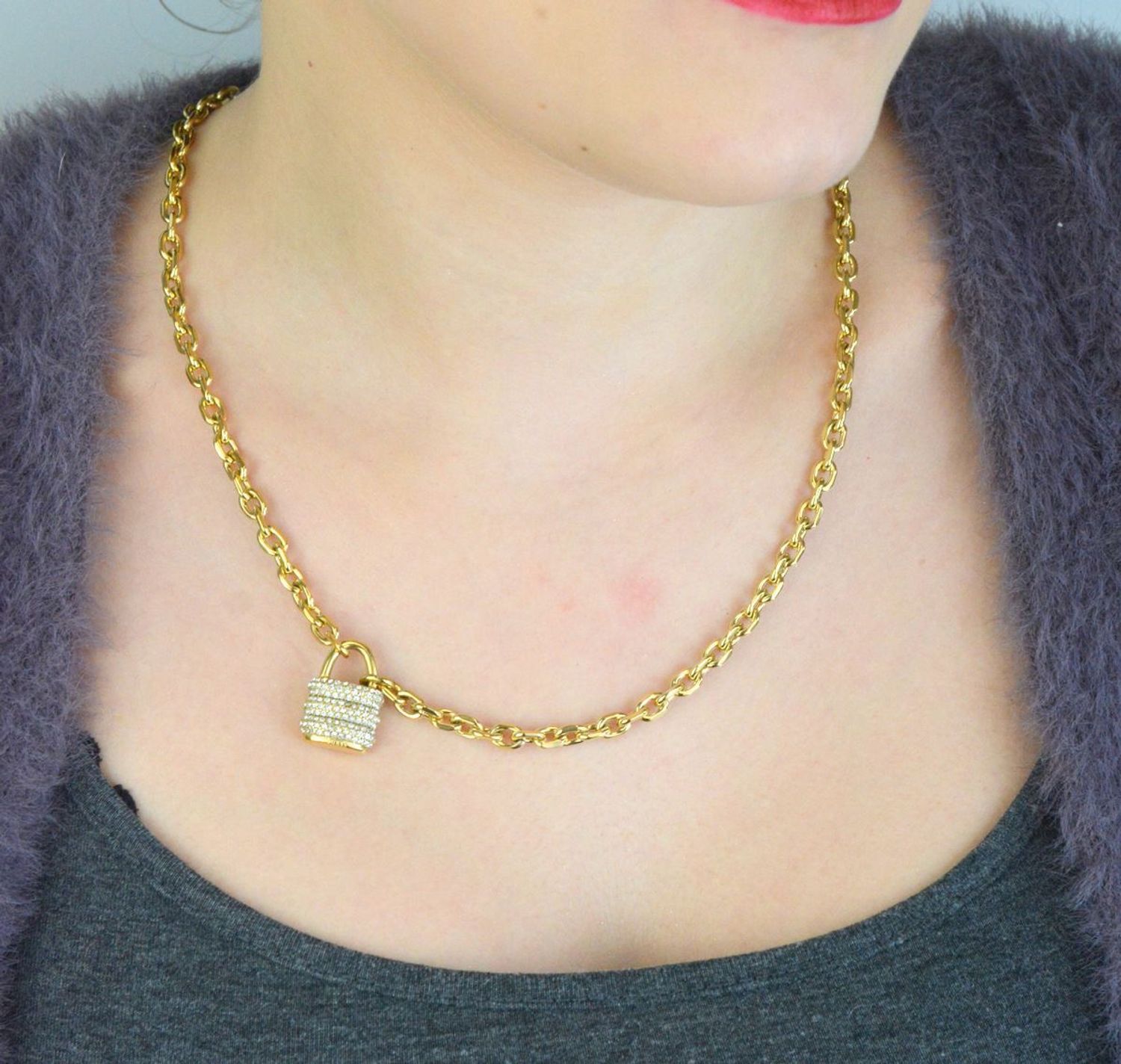 Pozłacany naszyjnik GUESS JUBN05415JWYGTU z zawieszką w kształcie kłódki i zdobieniem z kamieni. Wykonany ze stali szlachetnej, łączy elegancję i trwałość. Idealny na co dzień i wyjątkowe 1.jpg