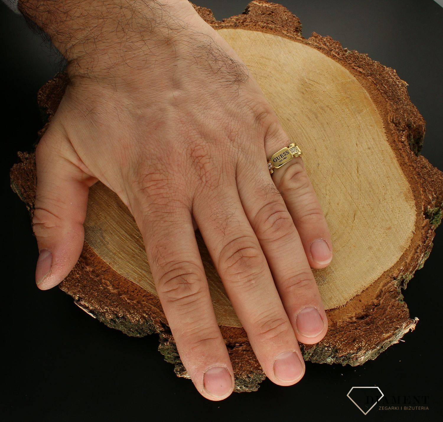 Pierścionek męski GUESS JUMR01344JWYG. Stalowy pierścionek męski pozłacany w formie obrączki. Pierścionek został ozdobiony w modny sposób czytelnym napisem GUESS . Pierścionek został wykonany z najwyższej jakości stali w kol (3).jpg