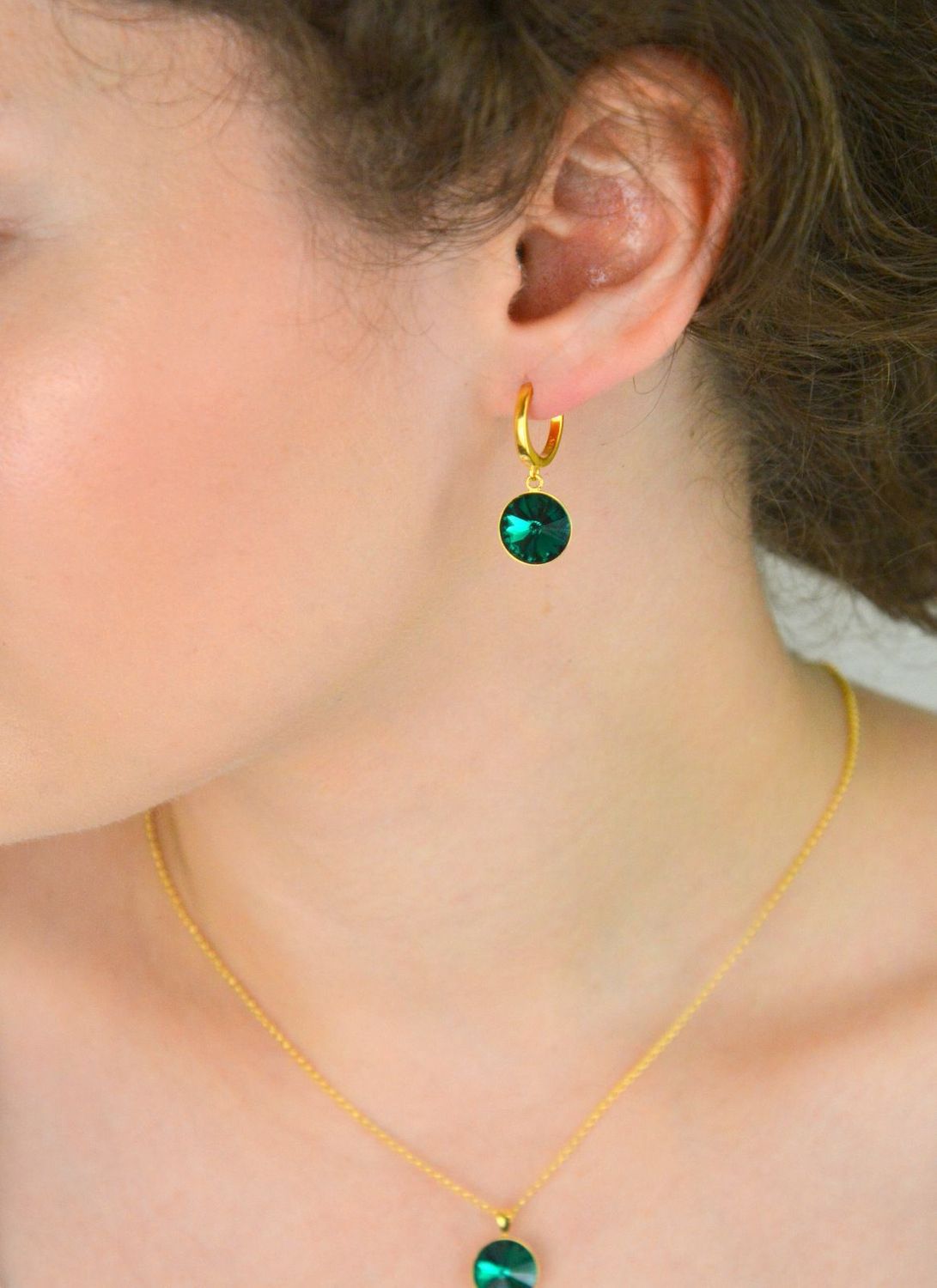 Kolczyki Spark z pozłacanego srebra 925, ozdobione kryształami w kolorze Emerald. Długość 2,7 cm, zapięcie na zatrzask. Stylowa elegancja na co dzień i wieczór.1.webp